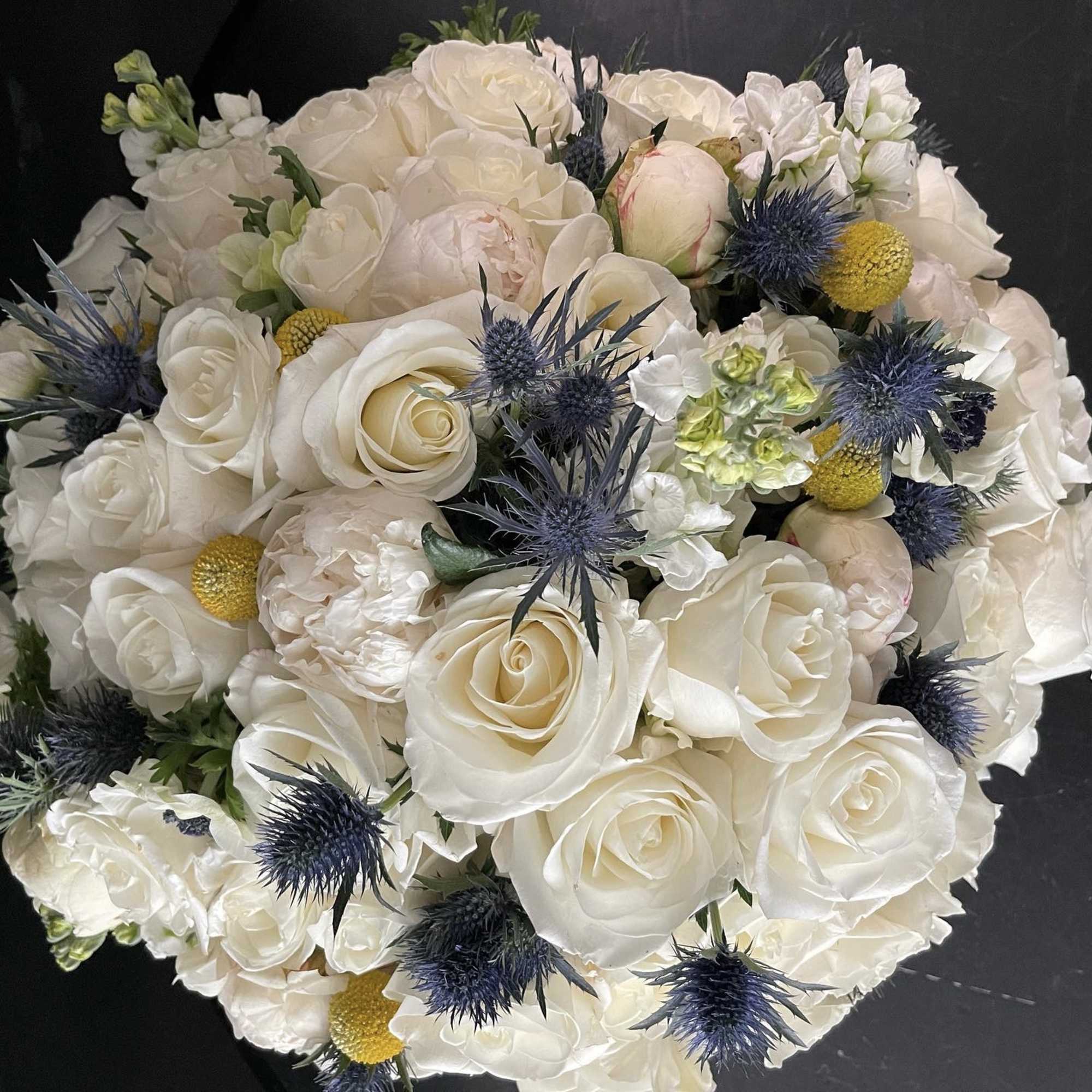 White rose bouquet with blue thistle and yellow accents, photo 4 of 9