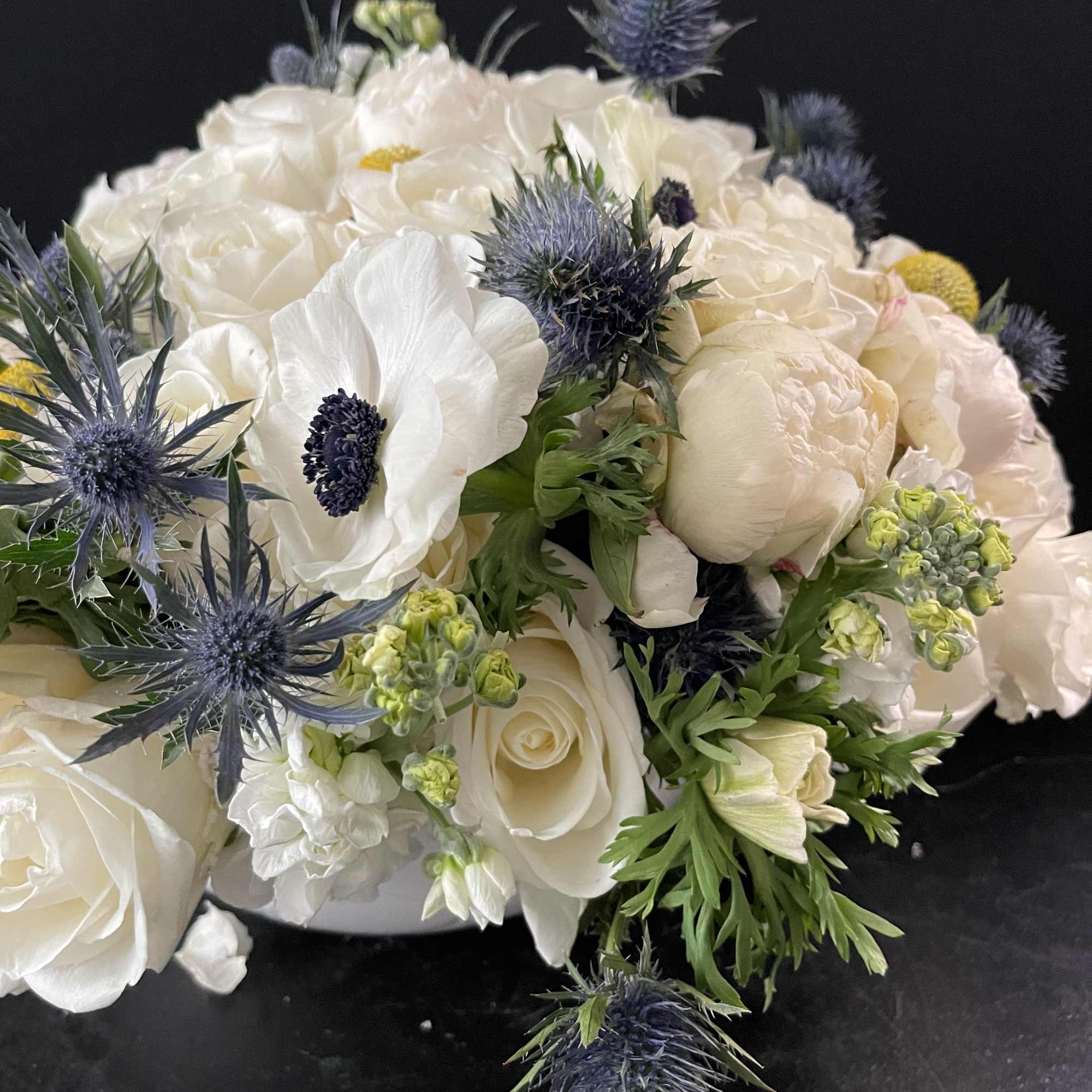 White bouquet with blue thistle-like flowers on a dark background