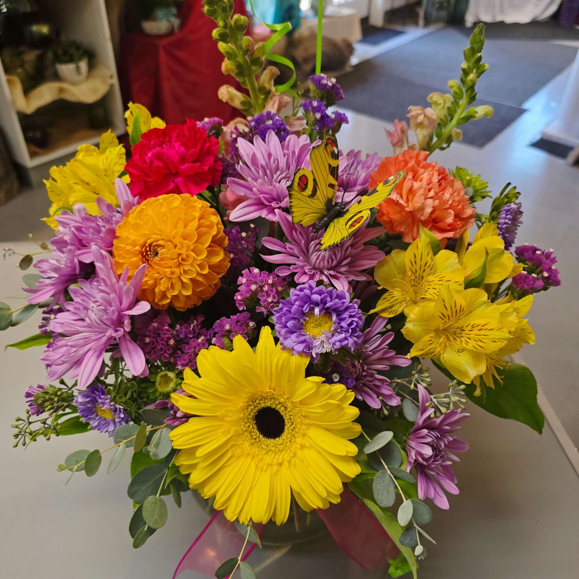 Bright mixed bouquet with gerbera daisies, chrysanthemums, and a butterfly pick