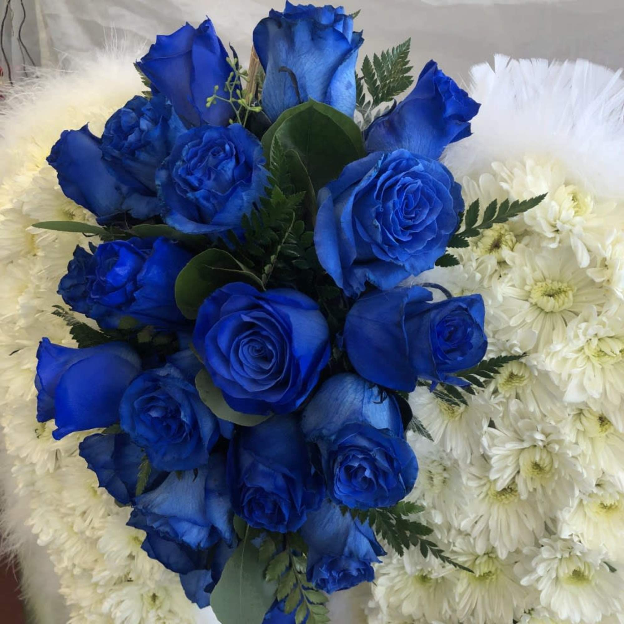 Blue roses arranged over white flowers and fur-like trim