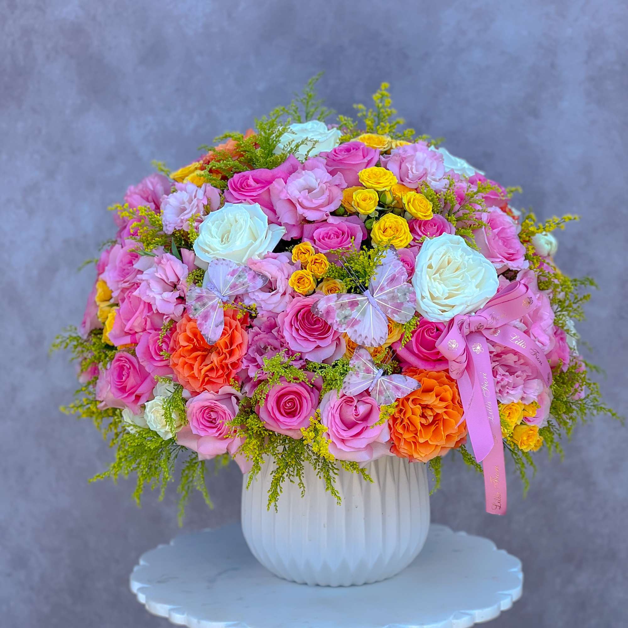 Large bouquet of pink, white, yellow, and orange roses in a white vase