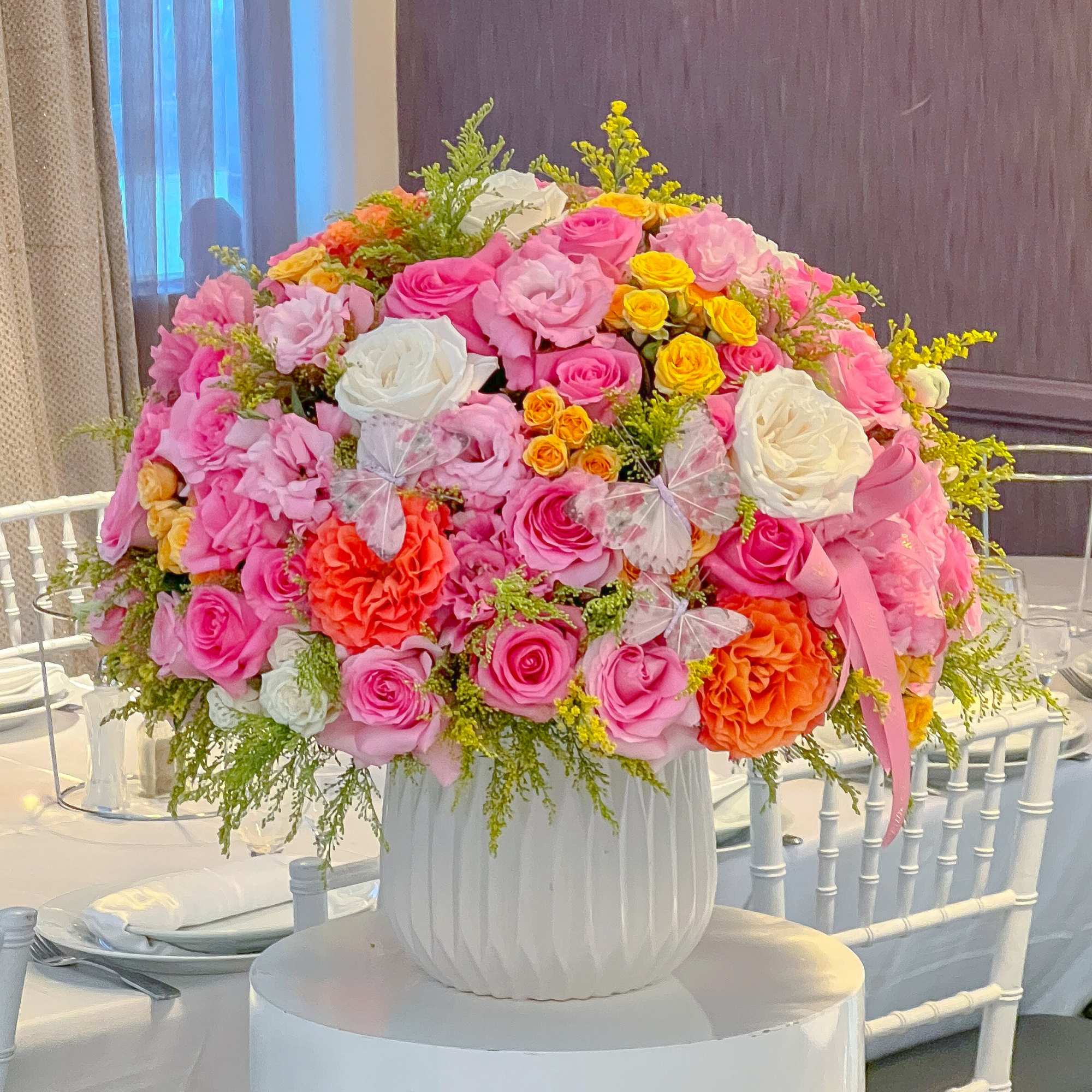 Large pink and white rose arrangement in a white vase on a table