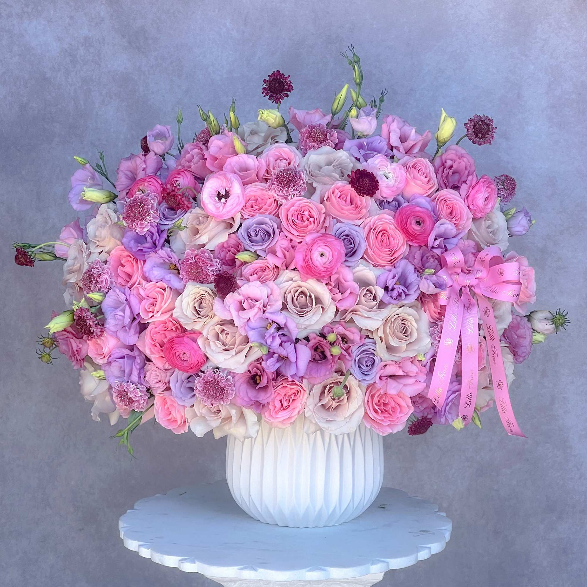 Large pastel bouquet of pink and lavender flowers in a white vase