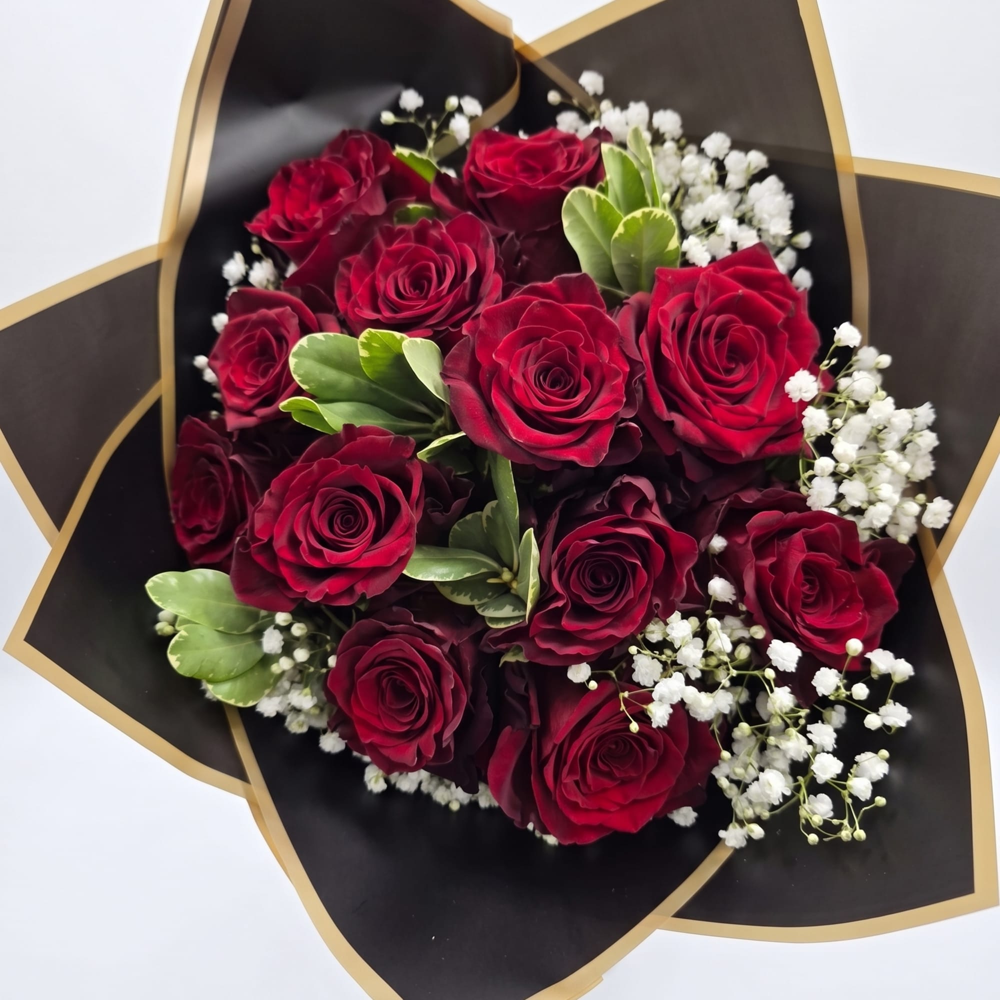 Bouquet of red roses with white baby's breath in black and gold wrap