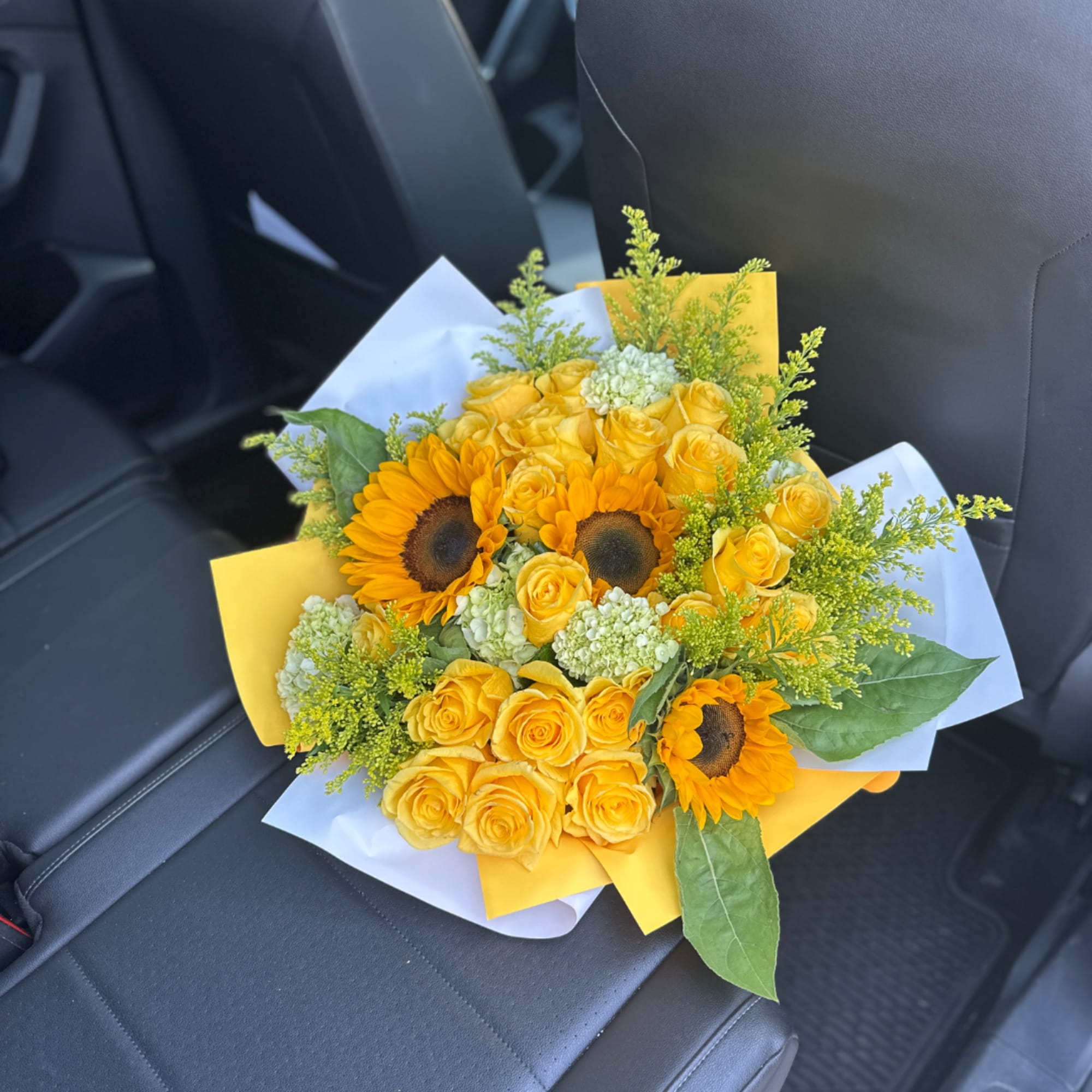 Yellow roses and sunflowers bouquet wrapped in white and yellow paper