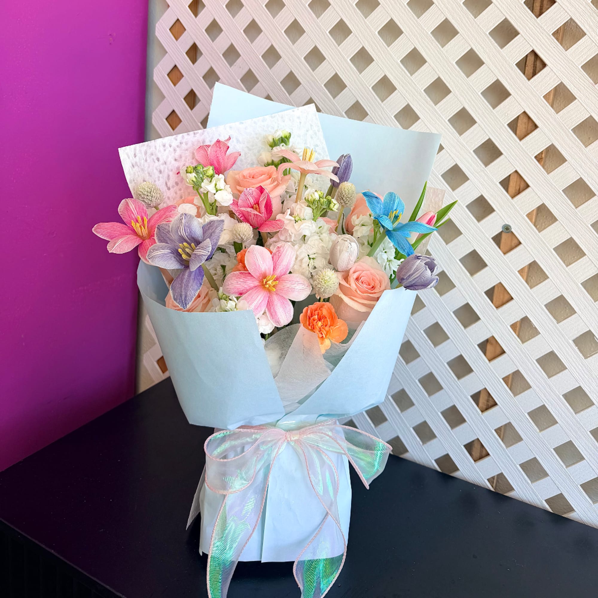 Pastel mixed bouquet wrapped in light blue paper with a ribbon