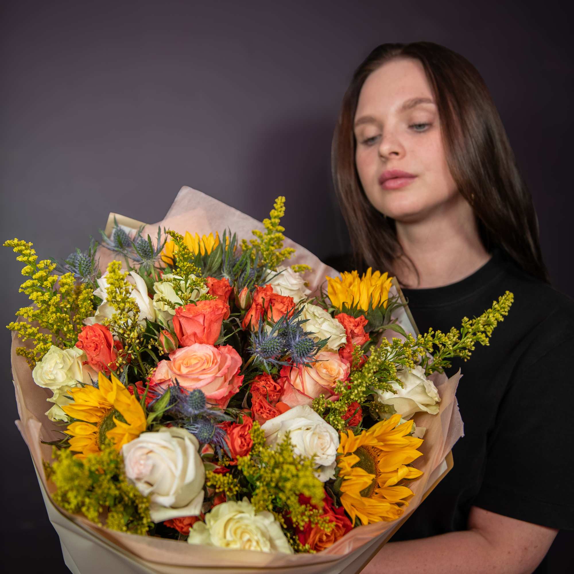 Large bouquet of roses and sunflowers wrapped in paper