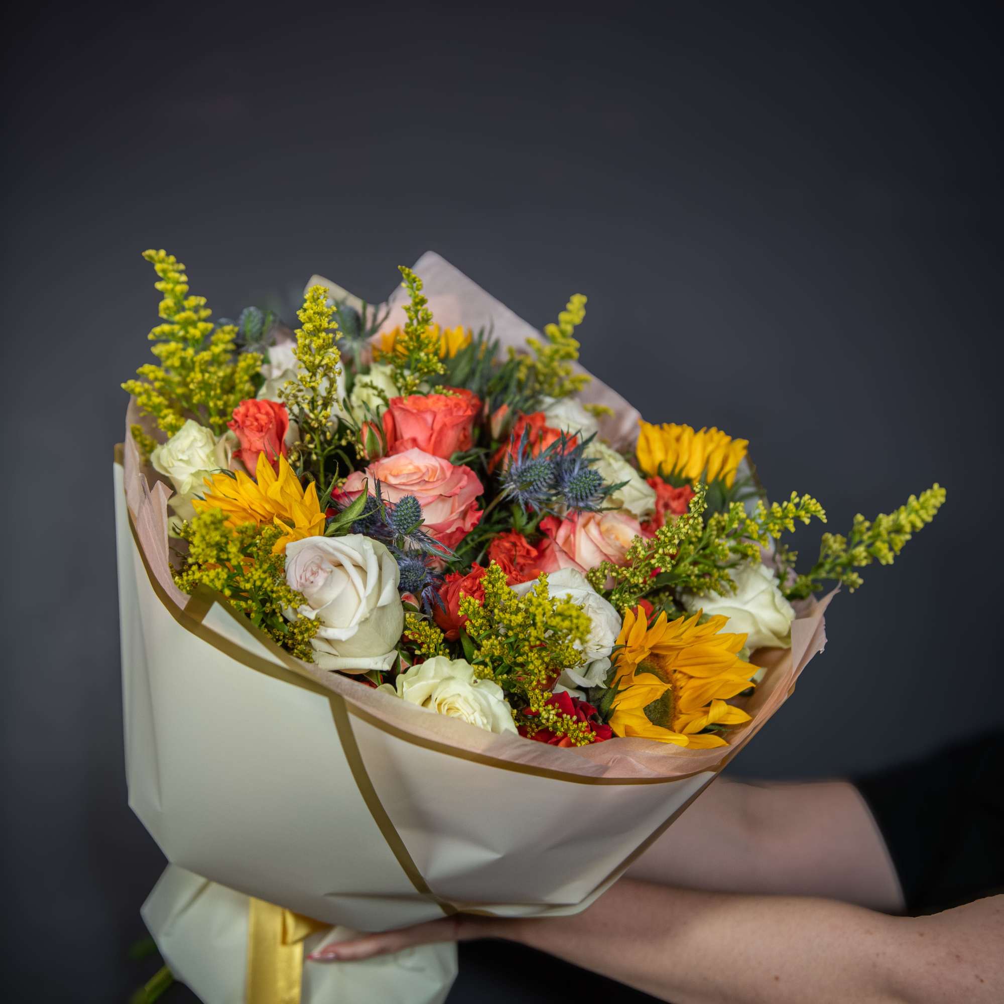 Bouquet of roses and sunflowers wrapped in cream paper