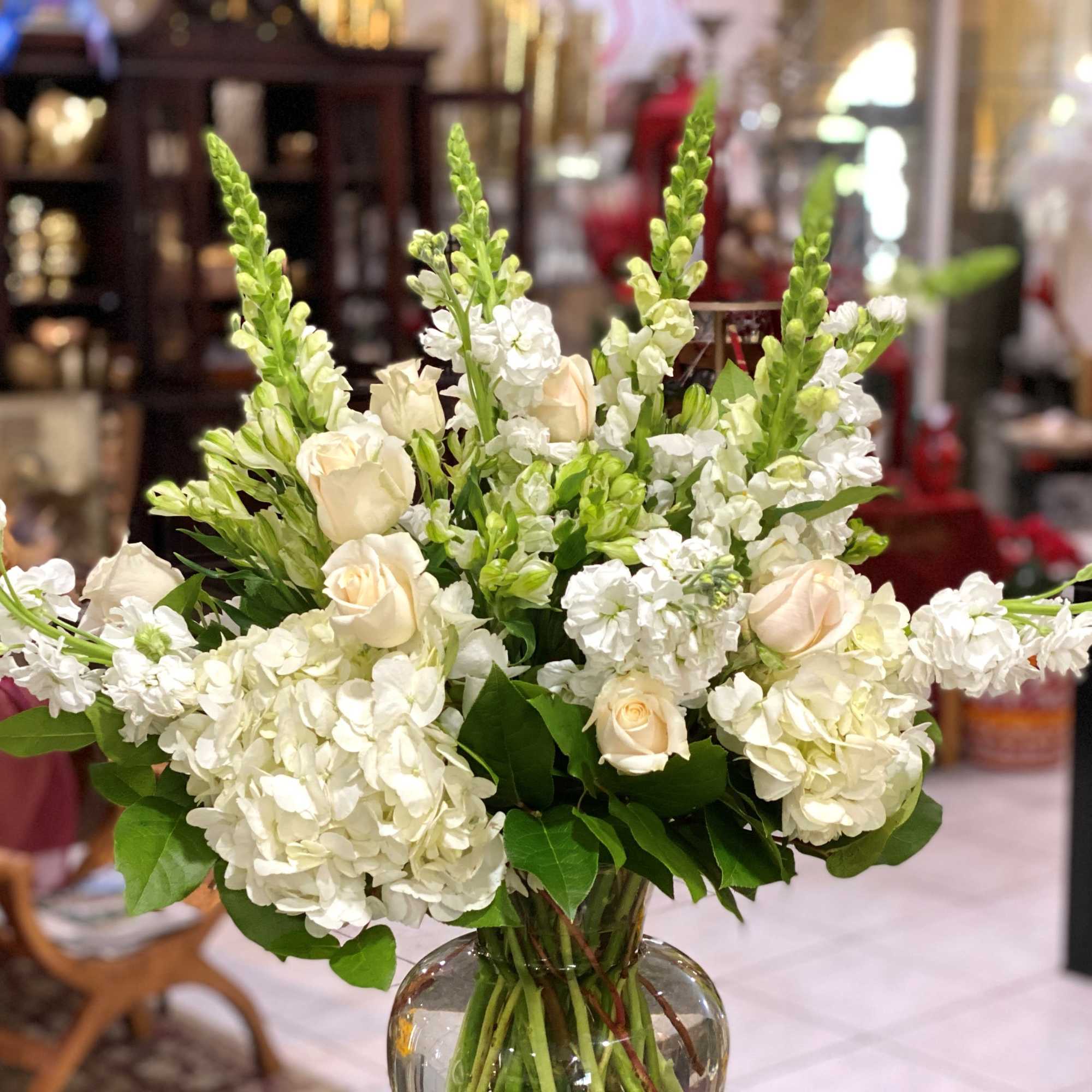 White flowers and cream roses arranged in a clear glass vase