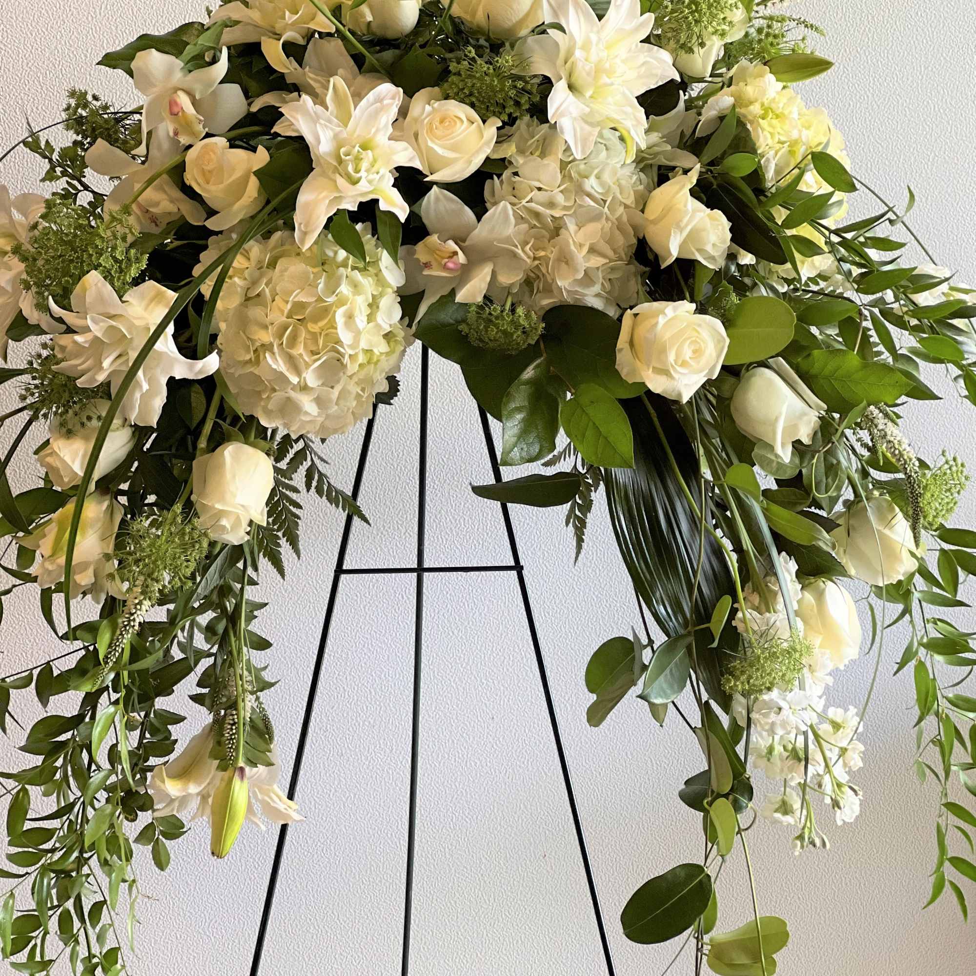 White floral funeral spray on a black stand