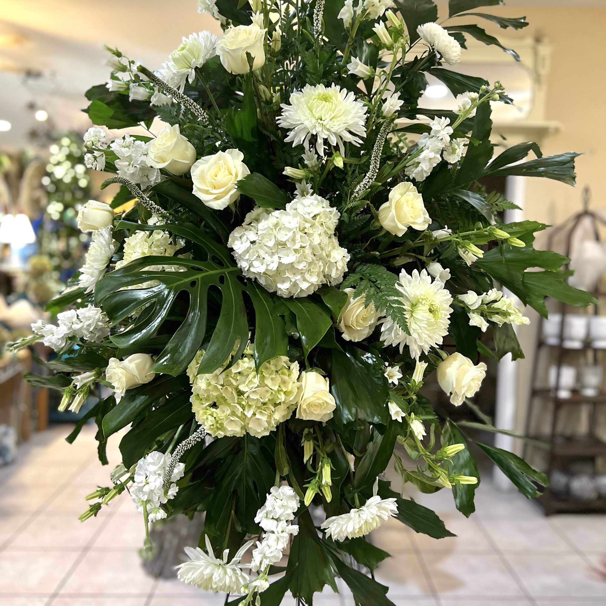 Large white floral standing spray with roses, hydrangea, and chrysanthemums