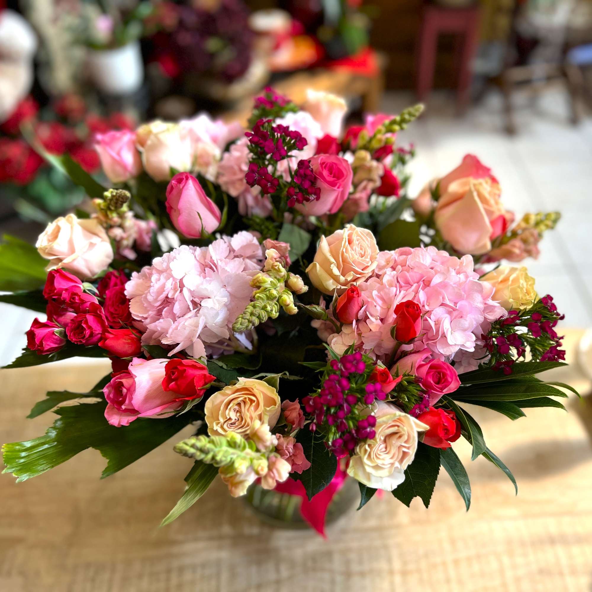 Mixed pink and peach rose bouquet with hydrangeas in a vase