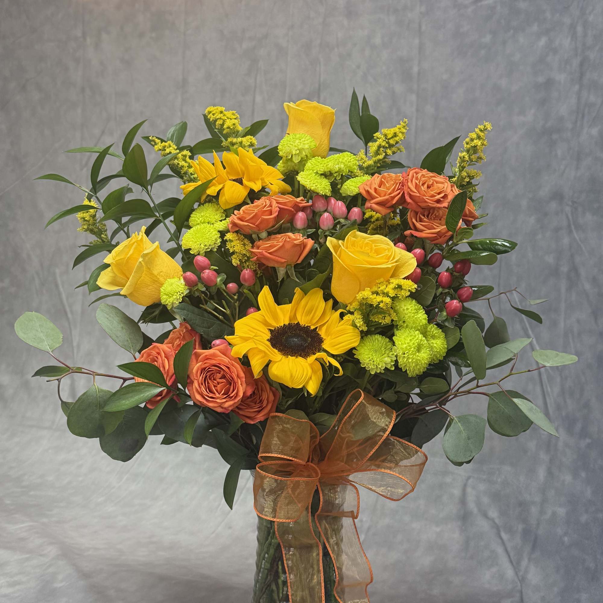 Bouquet of yellow sunflowers and orange roses in a glass vase, photo 2 of 2