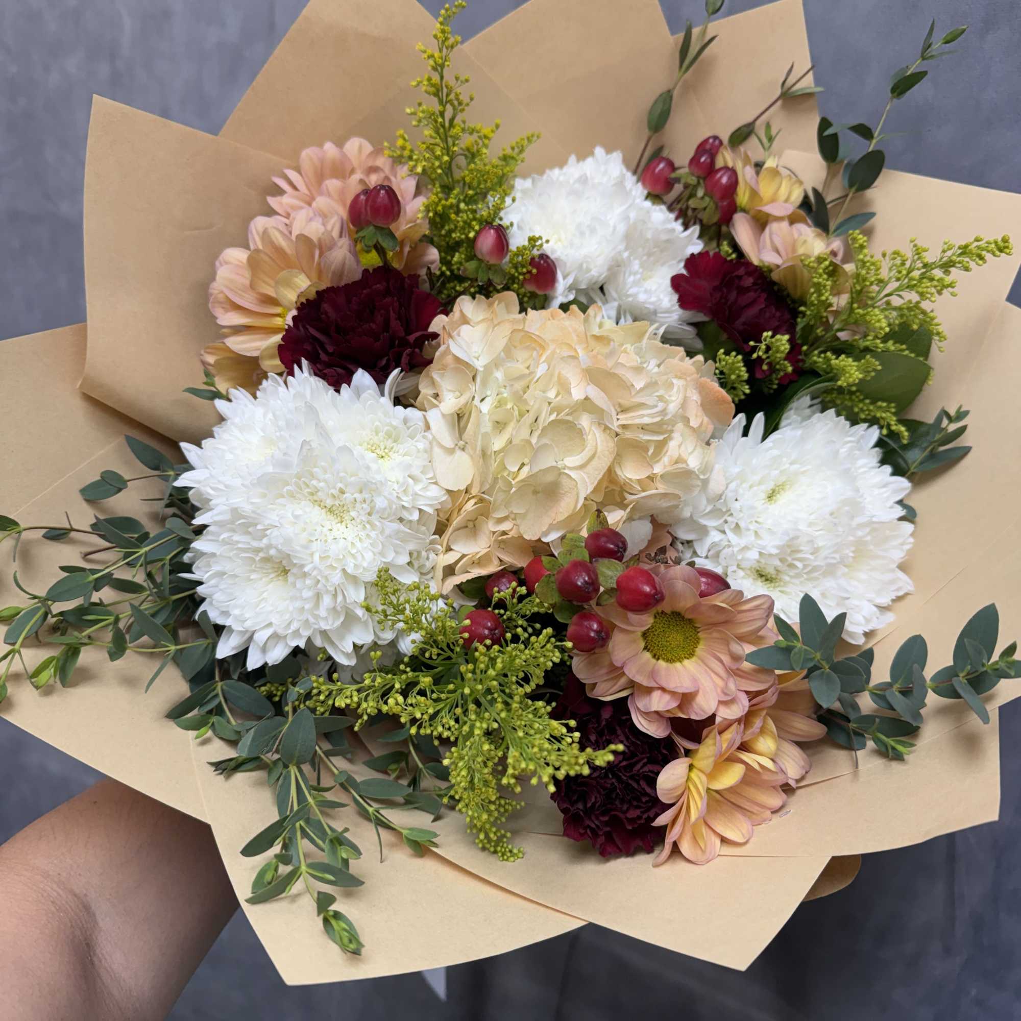 A charming blend of soft peach blooms, creamy hydrangea, white chrysanthemums, burgundy