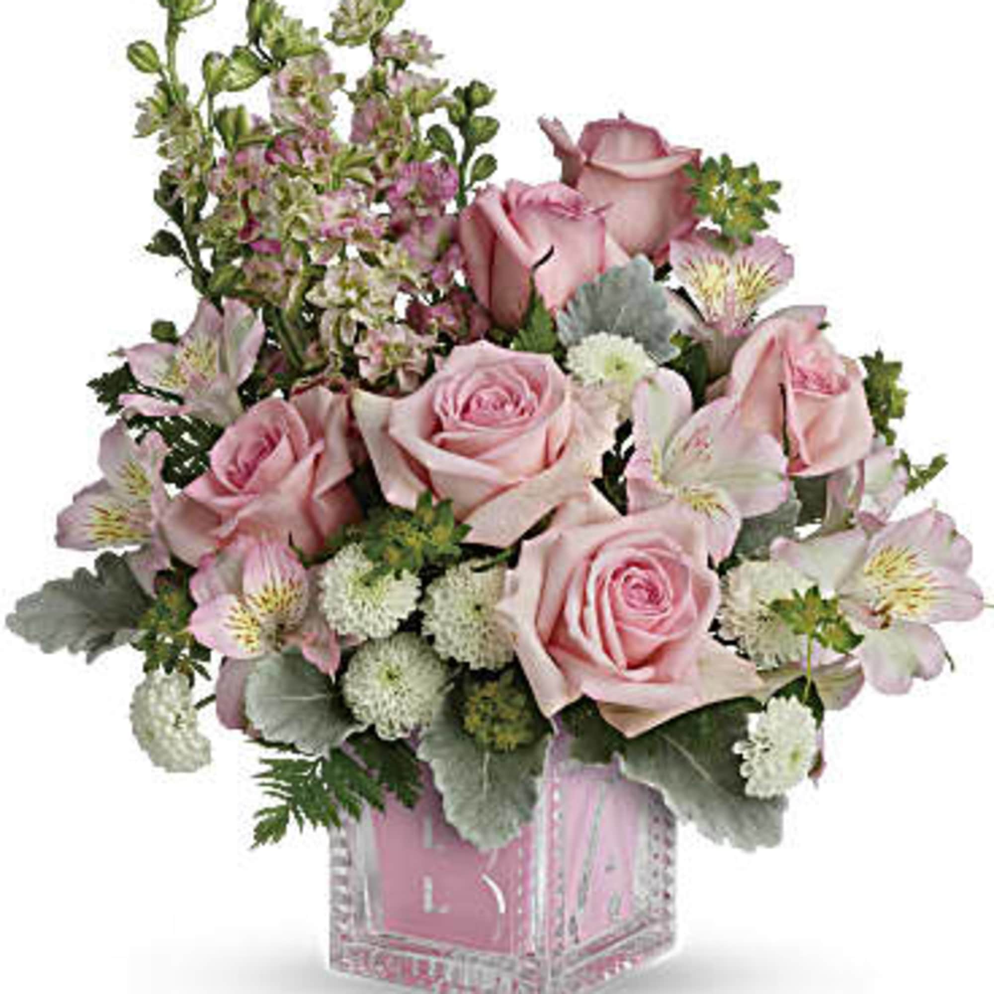 Pink roses and mixed blooms arranged in a clear square vase