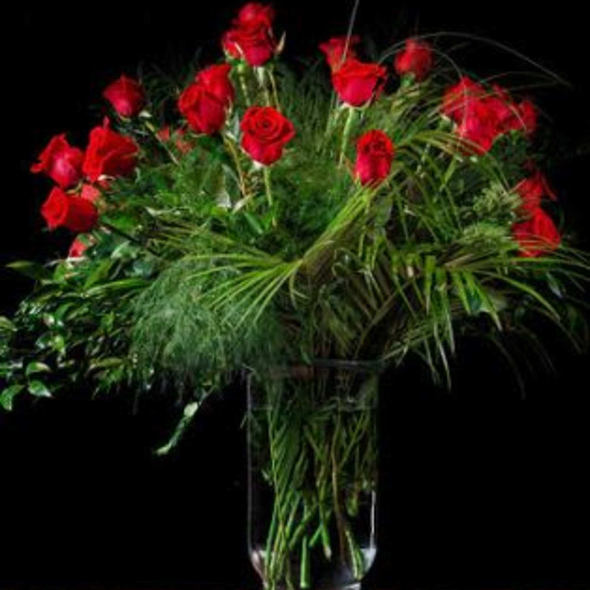 Tall bouquet of red roses in a clear glass vase