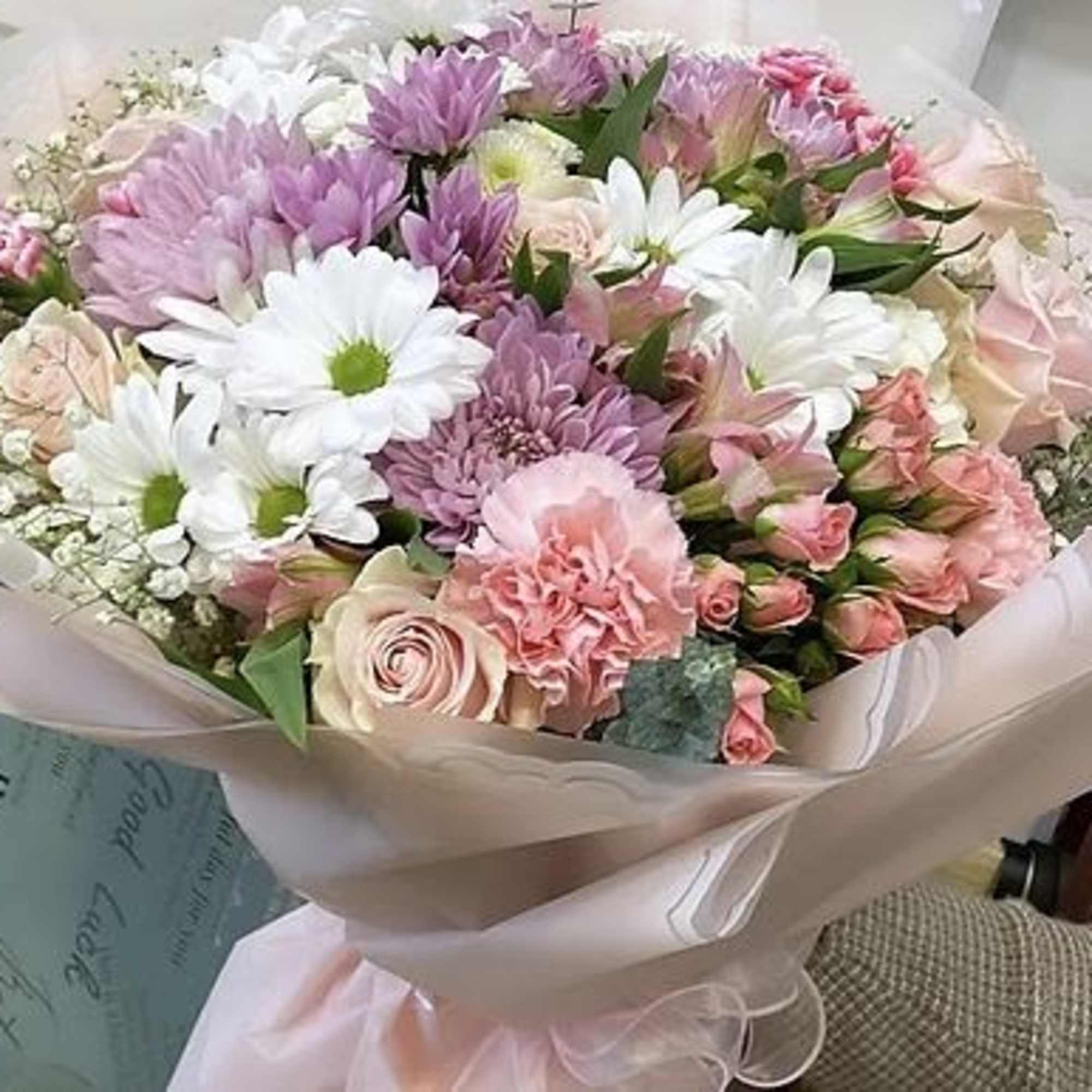 Bouquet of pink and white flowers wrapped in pale paper