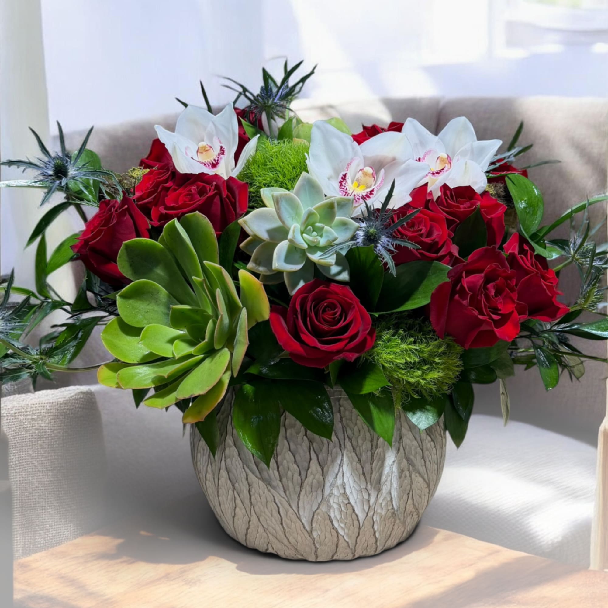 Red roses and white orchids arranged with succulents in a textured vase., photo 3 of 4