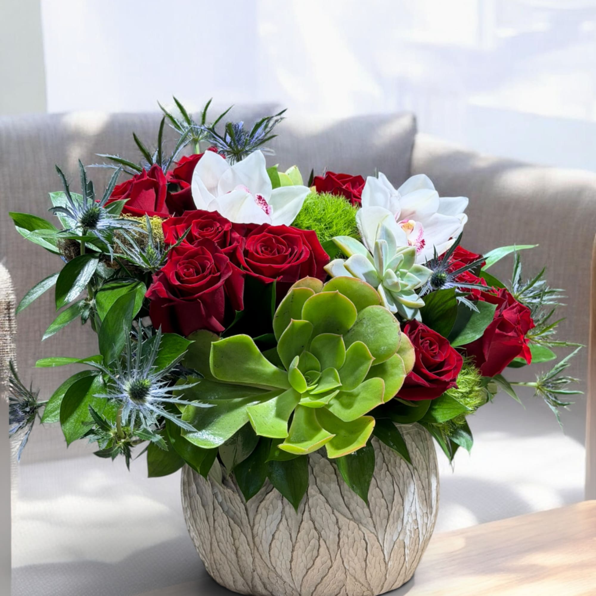 Red roses and white orchids arranged with succulents in a textured vase., photo 4 of 4