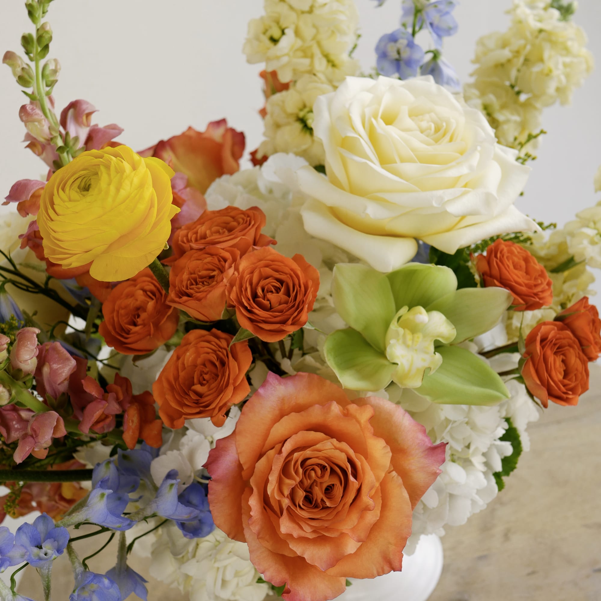 Colorful bouquet with orange, yellow, and white roses and blue flowers