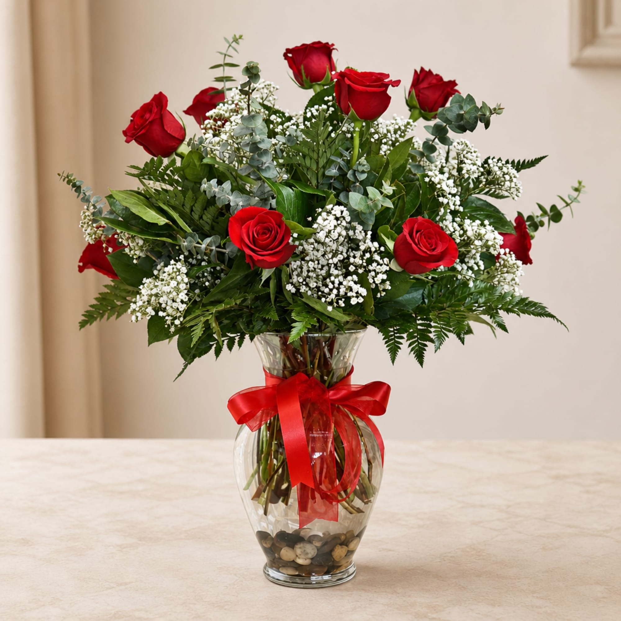 Red roses in a clear glass vase with a red ribbon