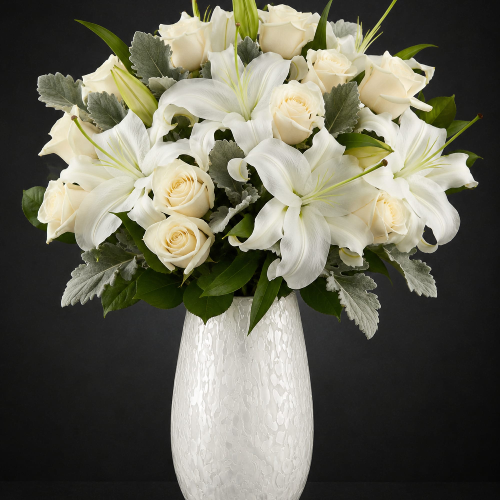 A refined mix of ivory roses and broad white lilies creates a