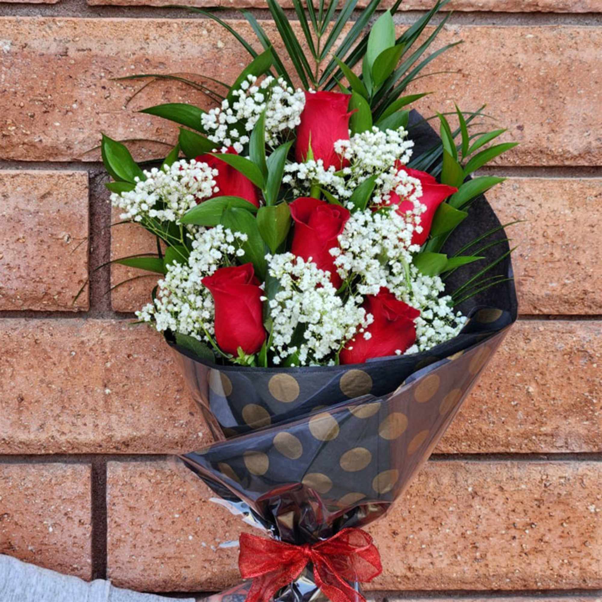 Bouquet of red roses and white baby's breath in black polka-dot wrap