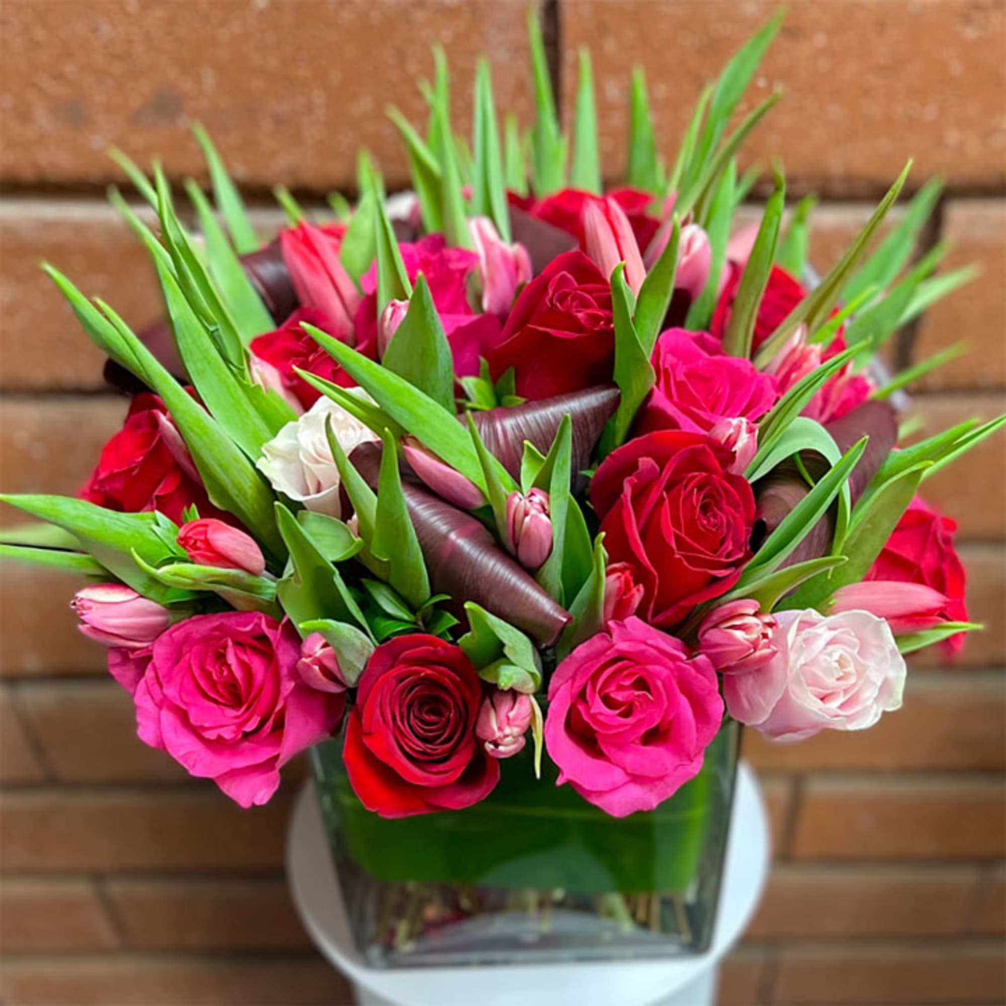 Bouquet of pink and red roses with tulips in a glass vase