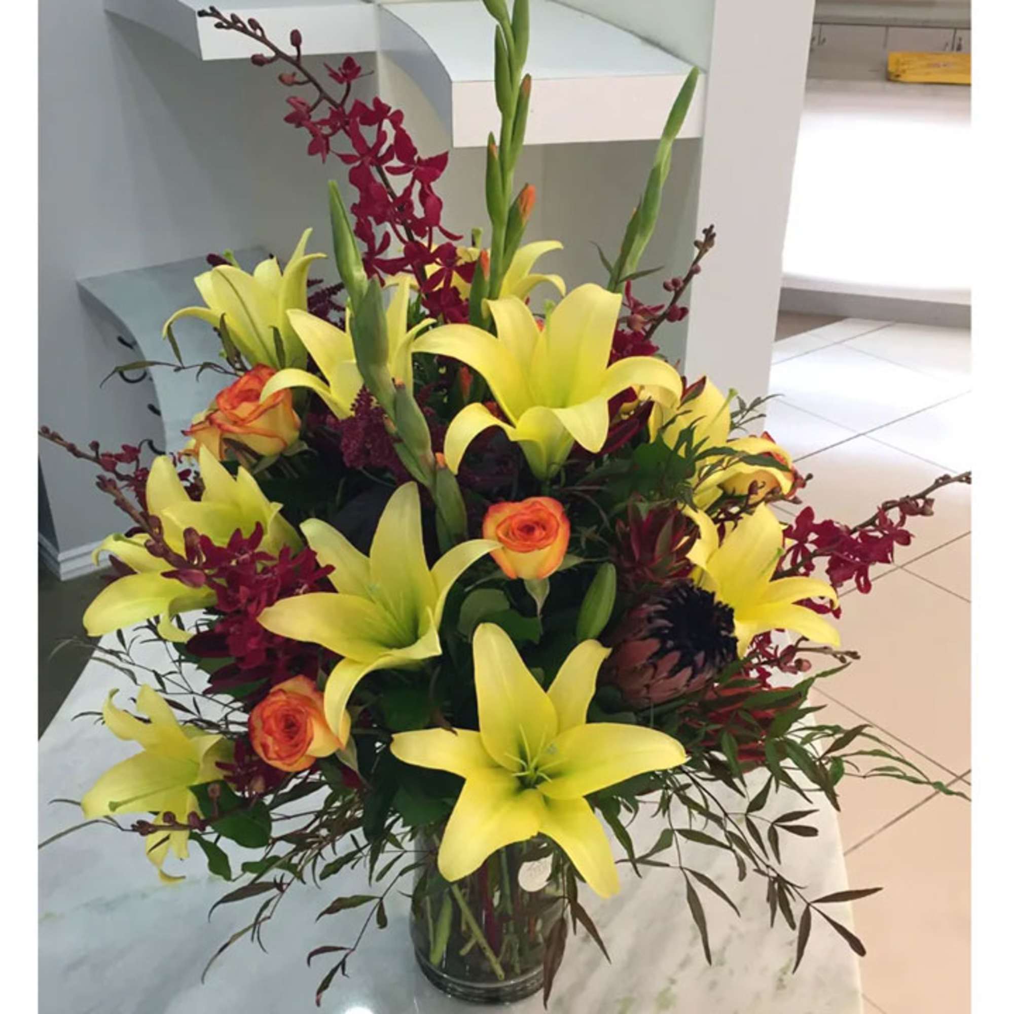 Yellow lilies and orange roses in a clear glass vase
