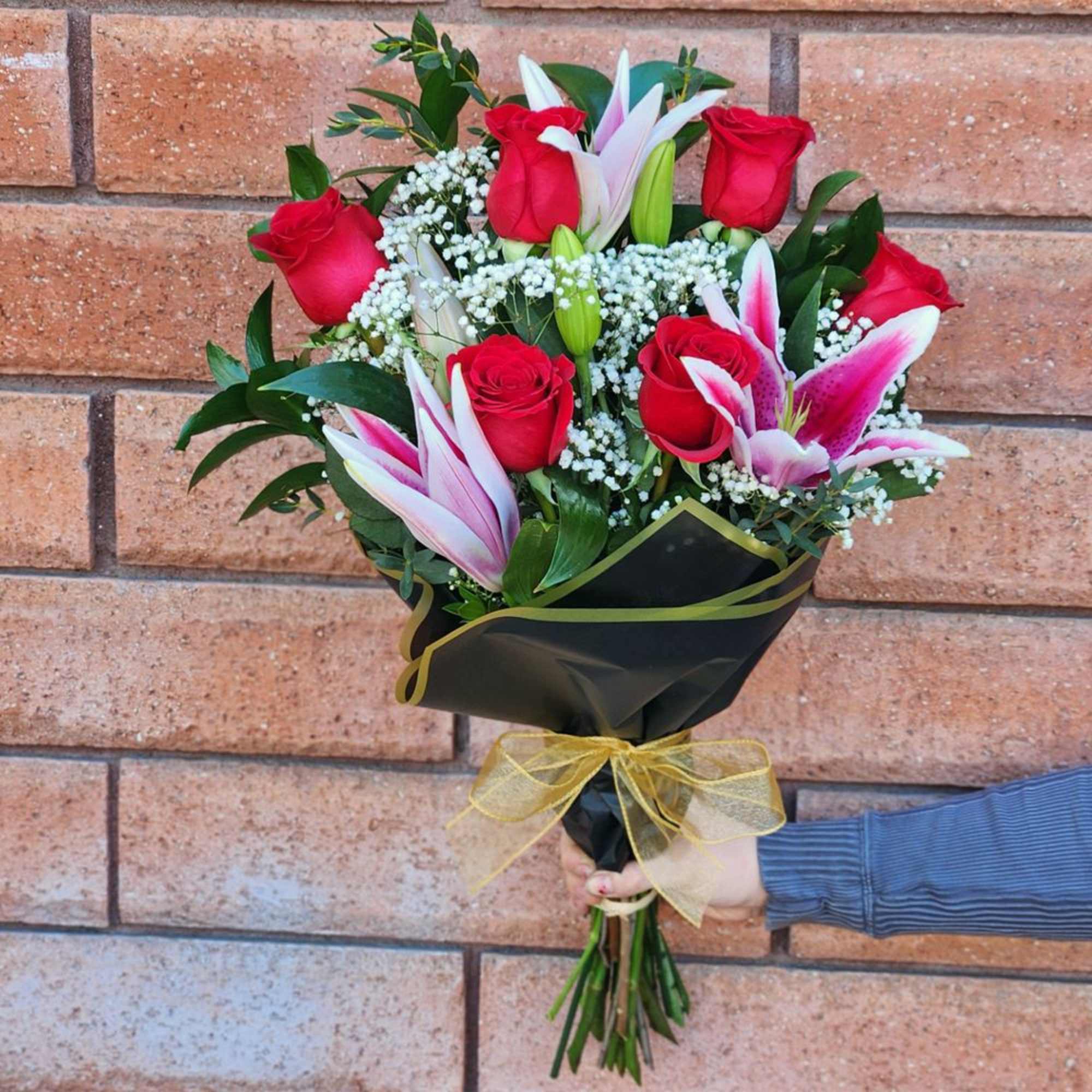 Bouquet of red roses and pink lilies wrapped in black paper