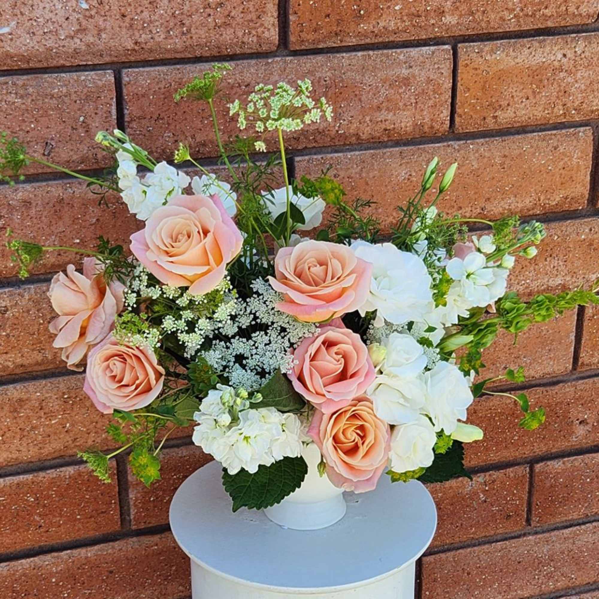 Peach and white roses arranged in a white vase
