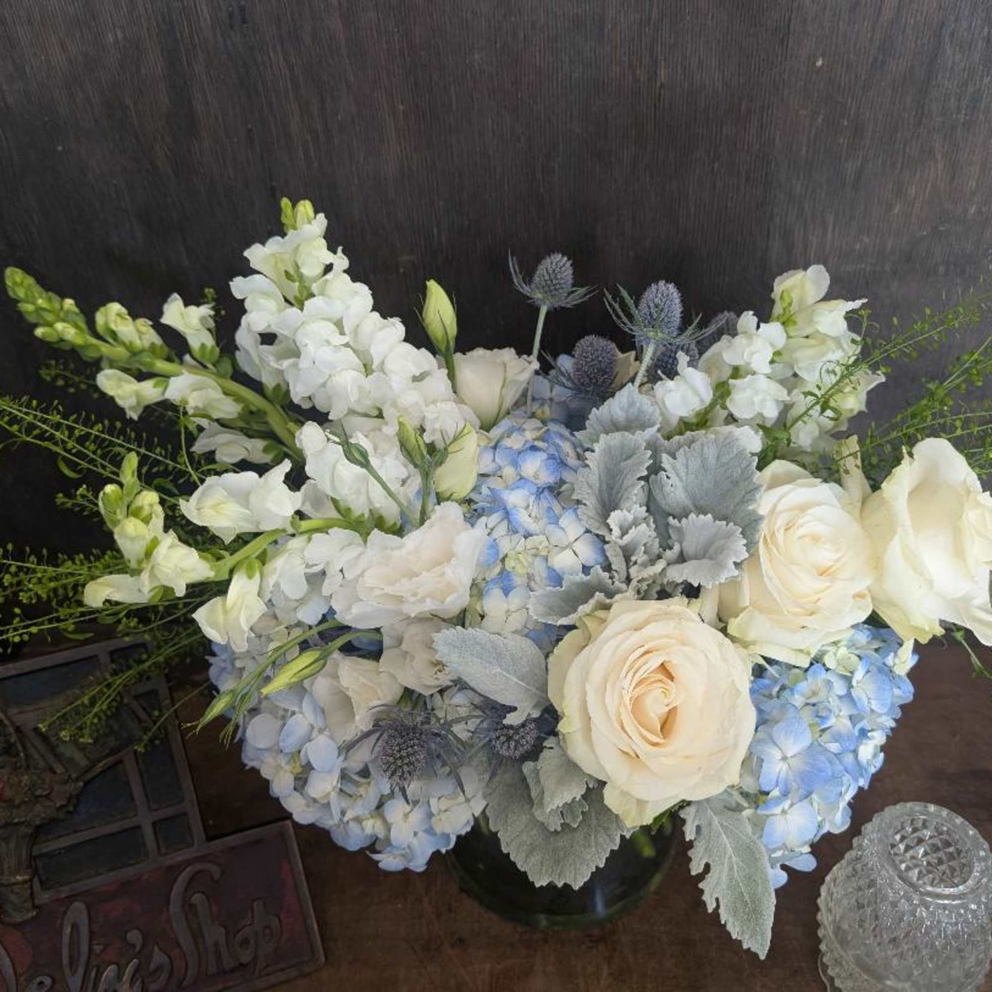White roses, blue hydrangeas, and white snapdragons in a vase
