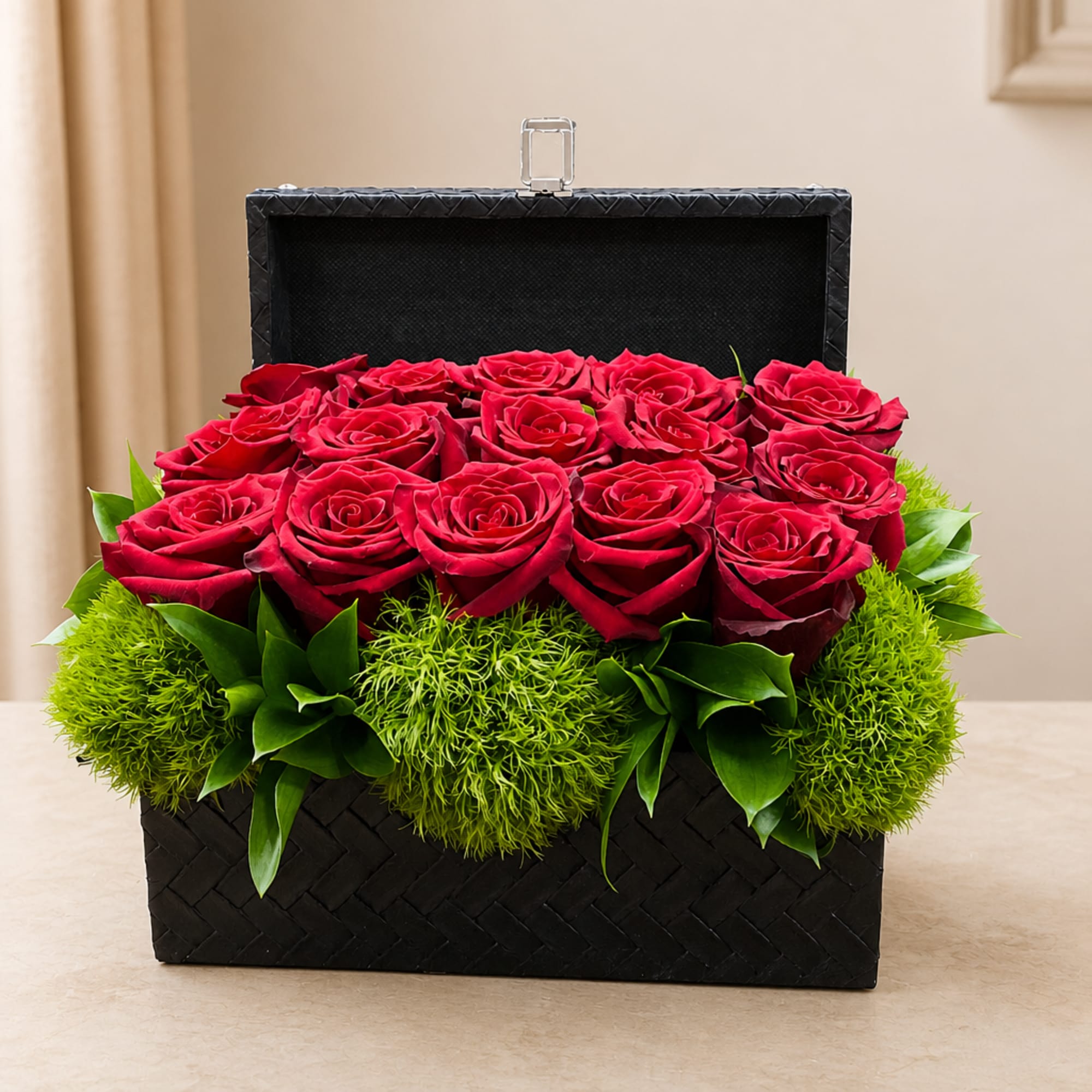 Red roses arranged in a black woven box with green accents