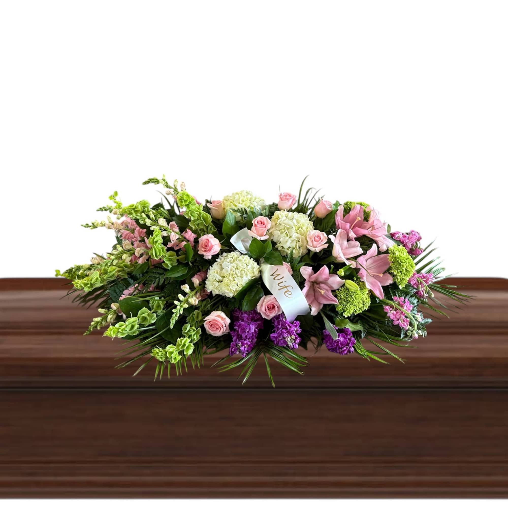 Pink and white floral casket spray on a wooden casket