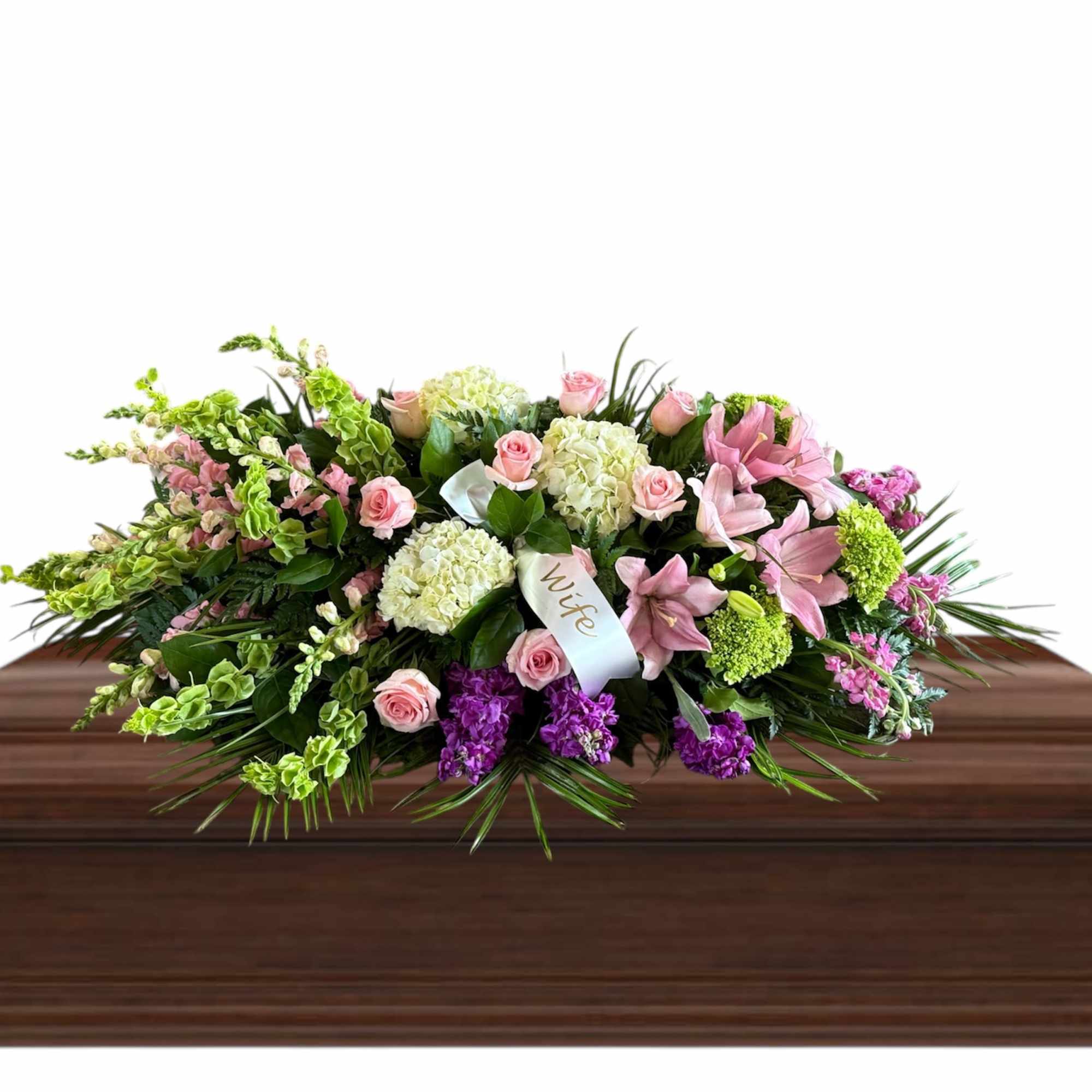 Pink and white floral spray on a wooden casket