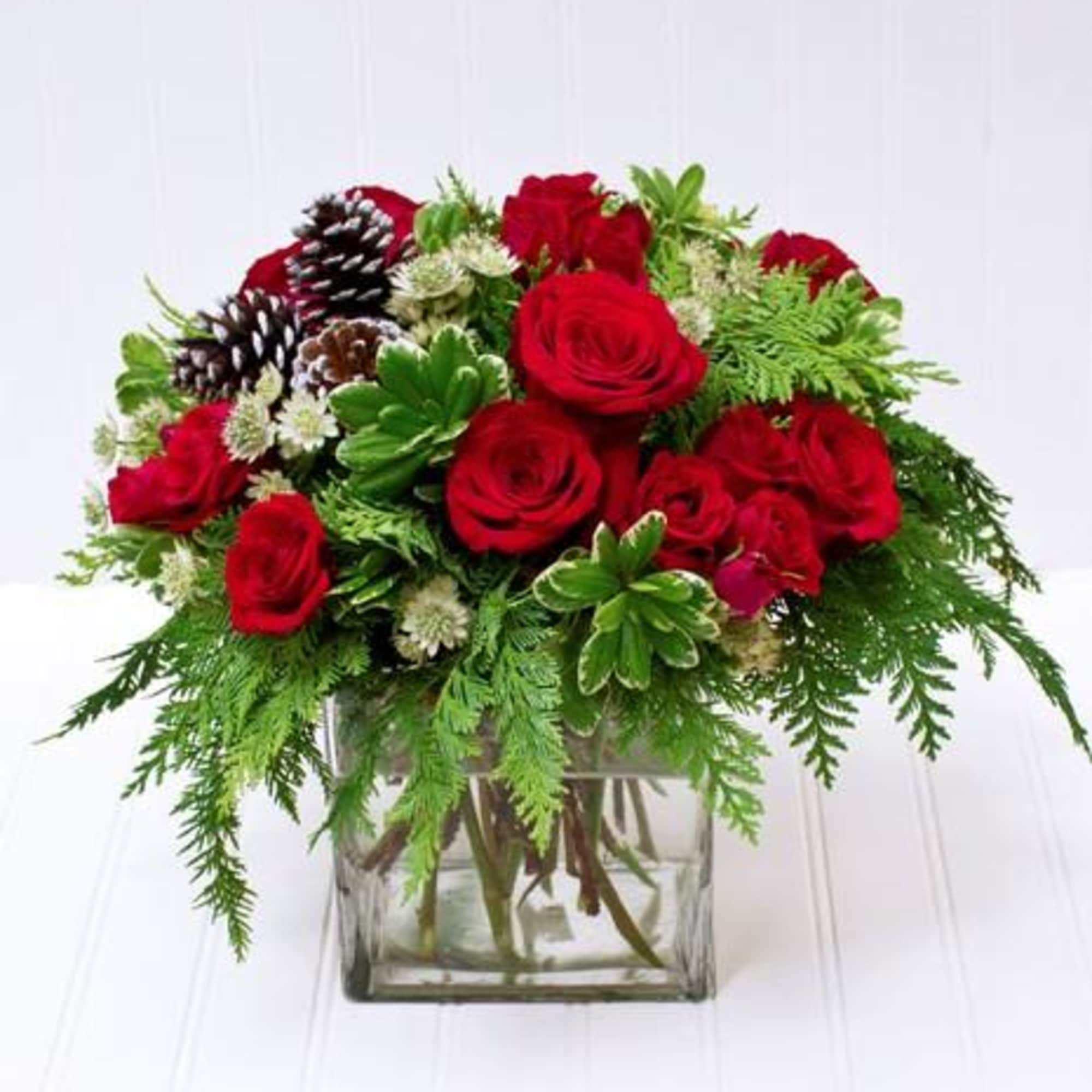 cube with red green and white flowers arranged with pine cones 