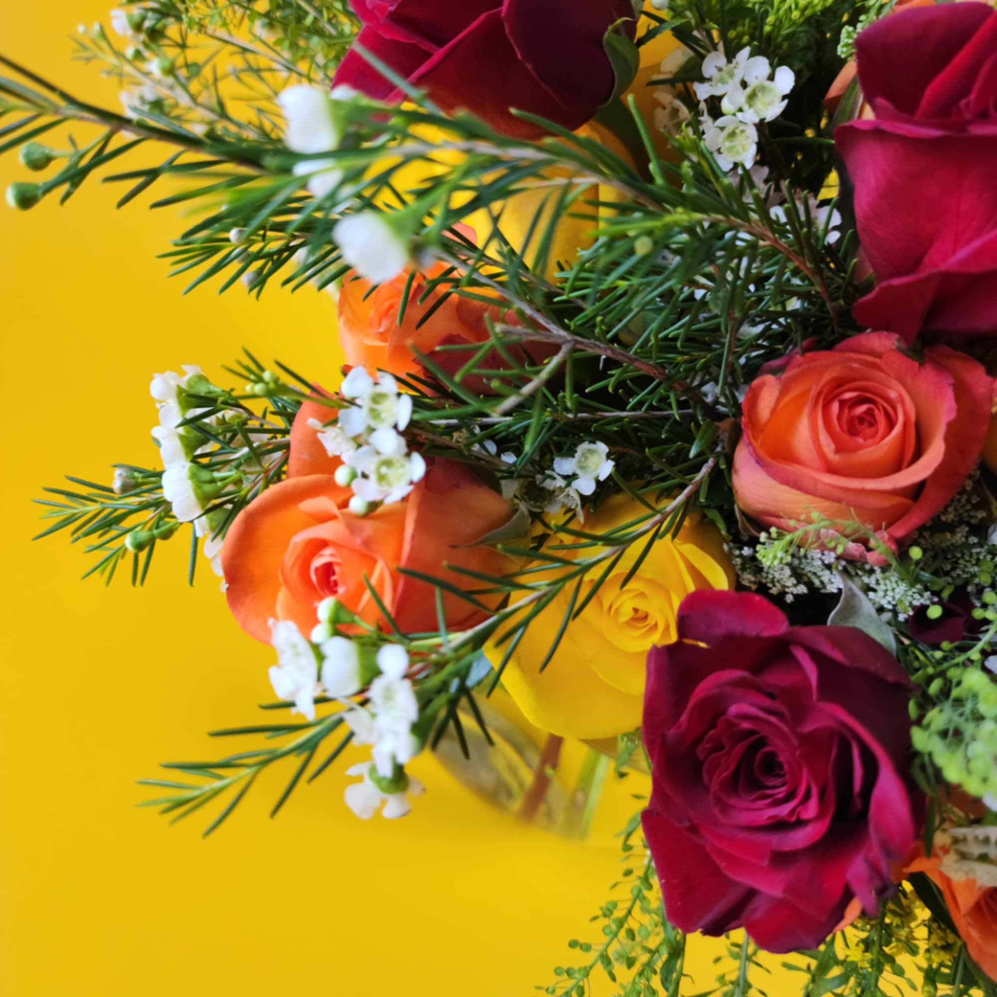 Bouquet of red, orange, and yellow roses with small white filler flowers