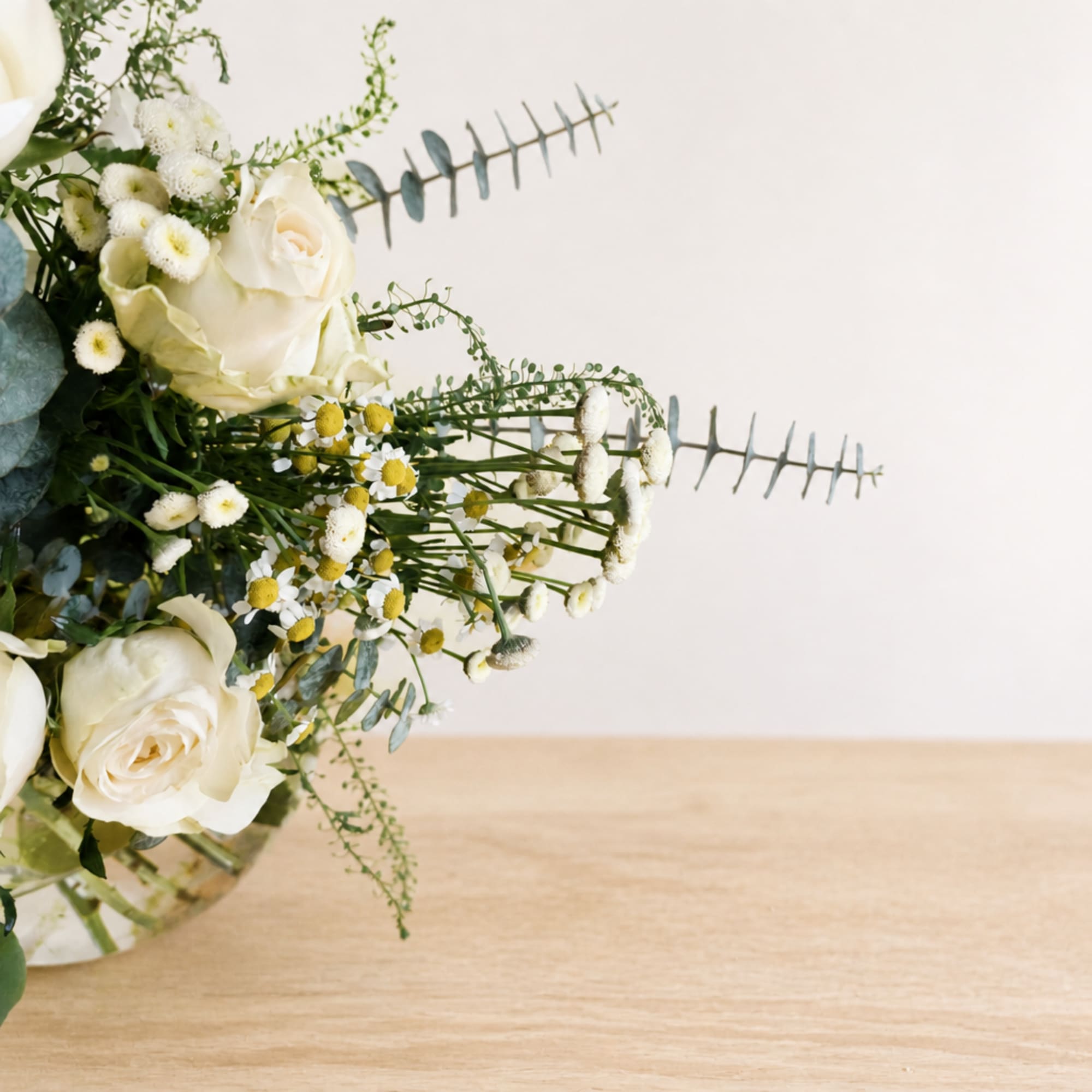 White roses and small daisies in a glass vase