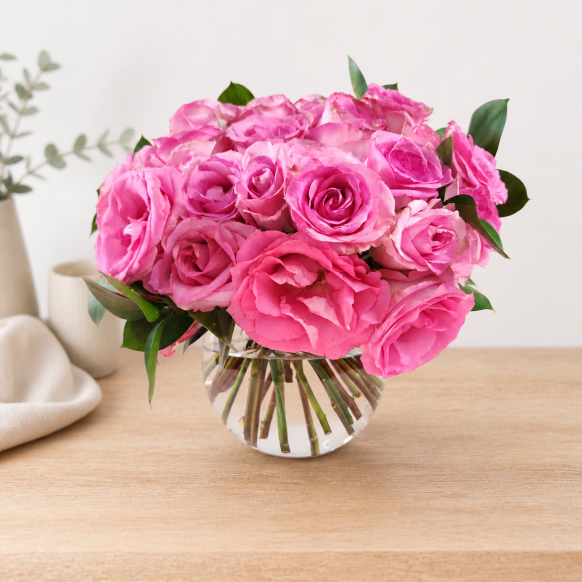 Pink rose bouquet in a clear glass vase on a wooden table