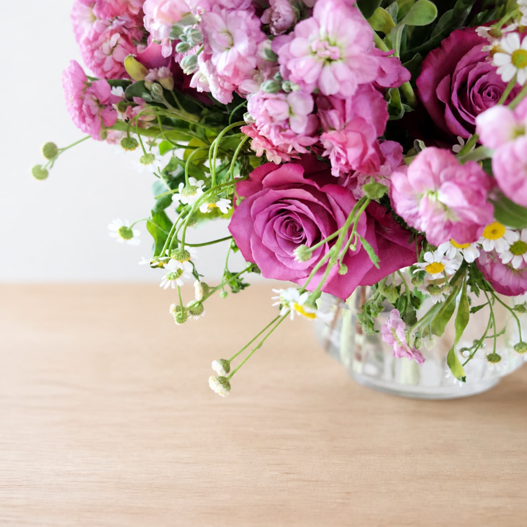Pink roses and mixed pink blooms in a clear glass vase