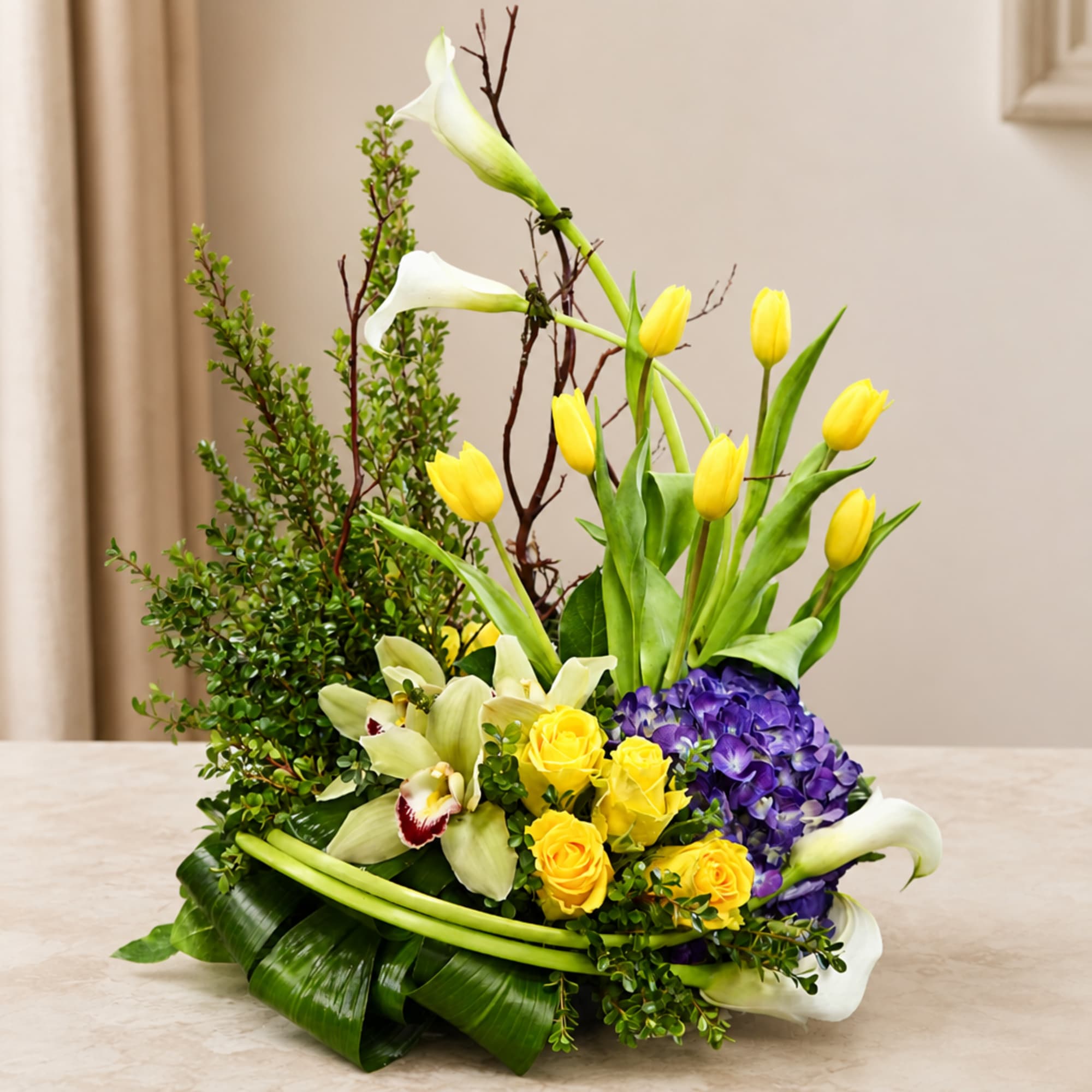 Yellow tulips, white calla lilies, purple hydrangea, and yellow roses in a low arrangement