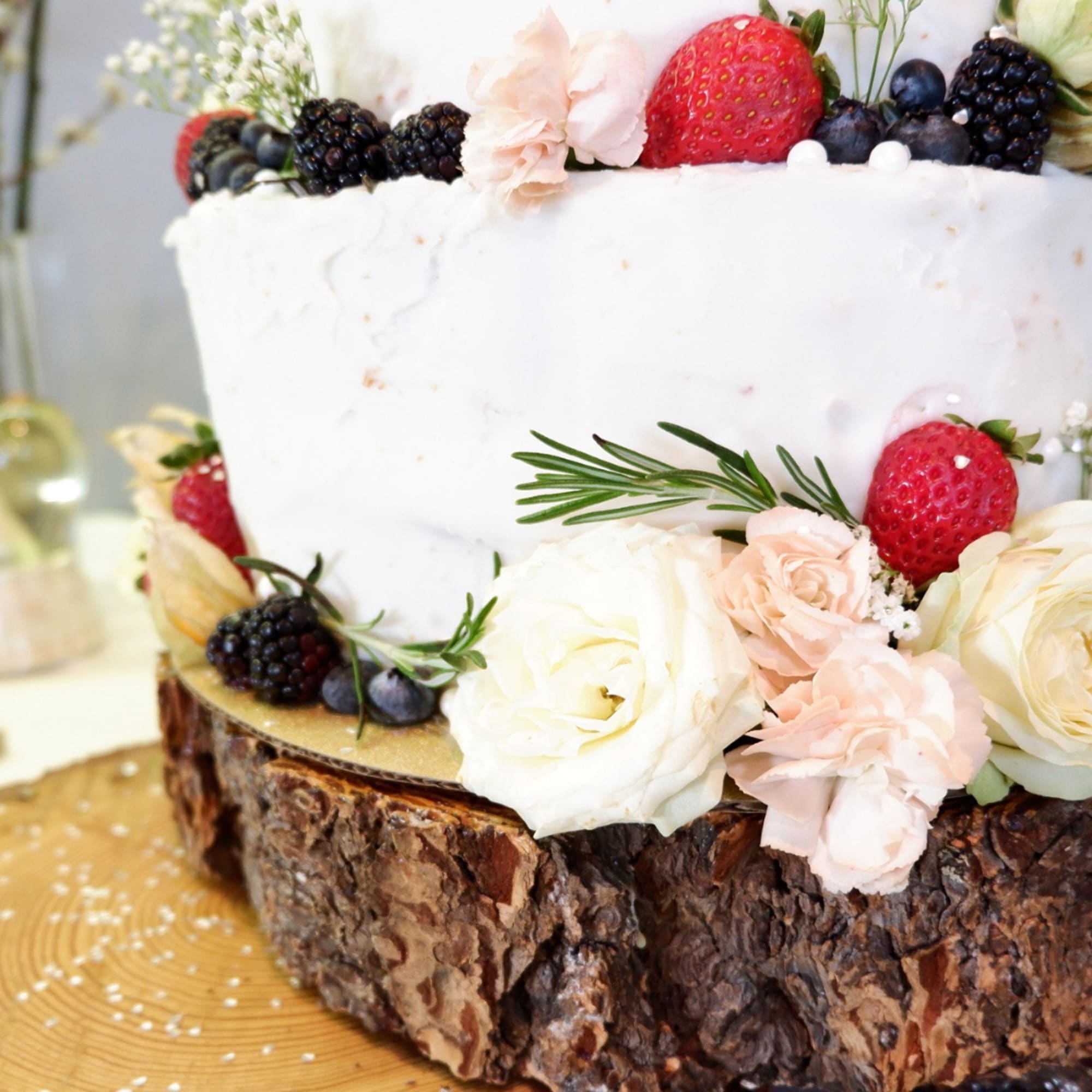 White frosted cake decorated with berries and pale flowers