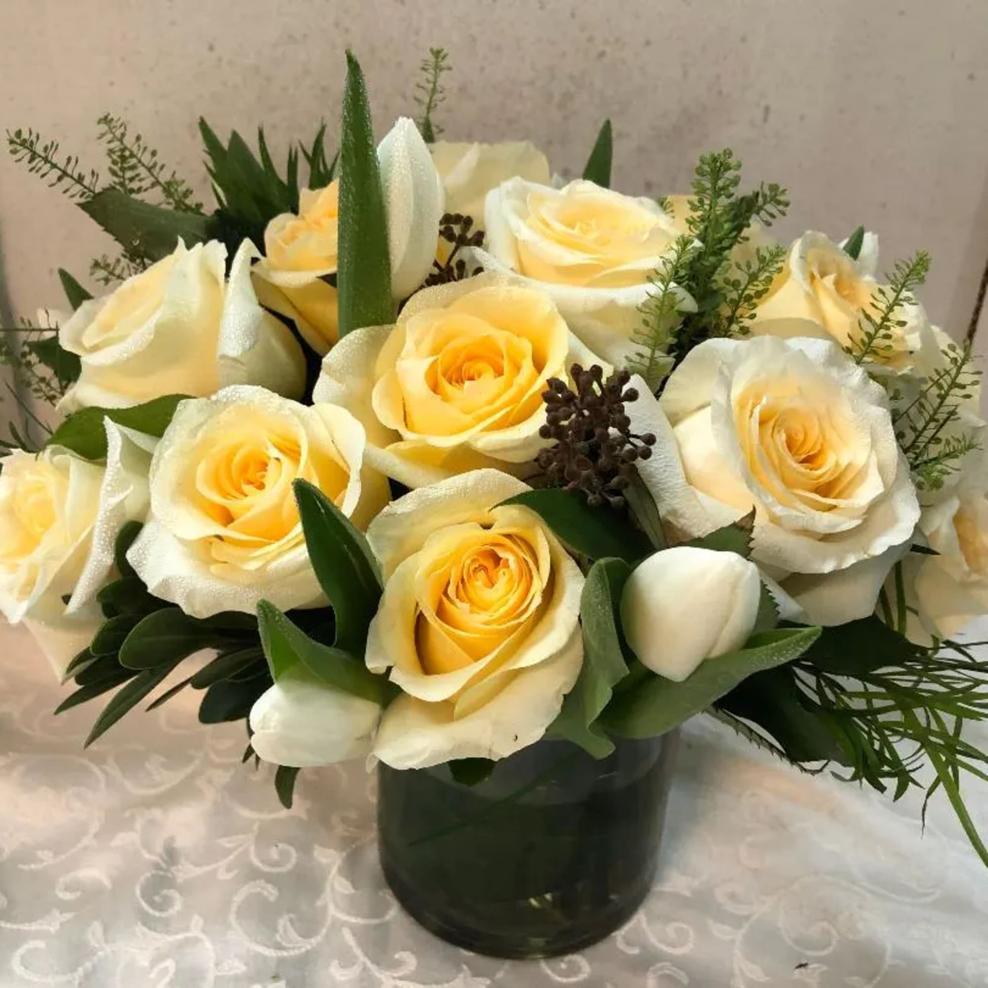 Cream and yellow roses arranged in a dark glass vase