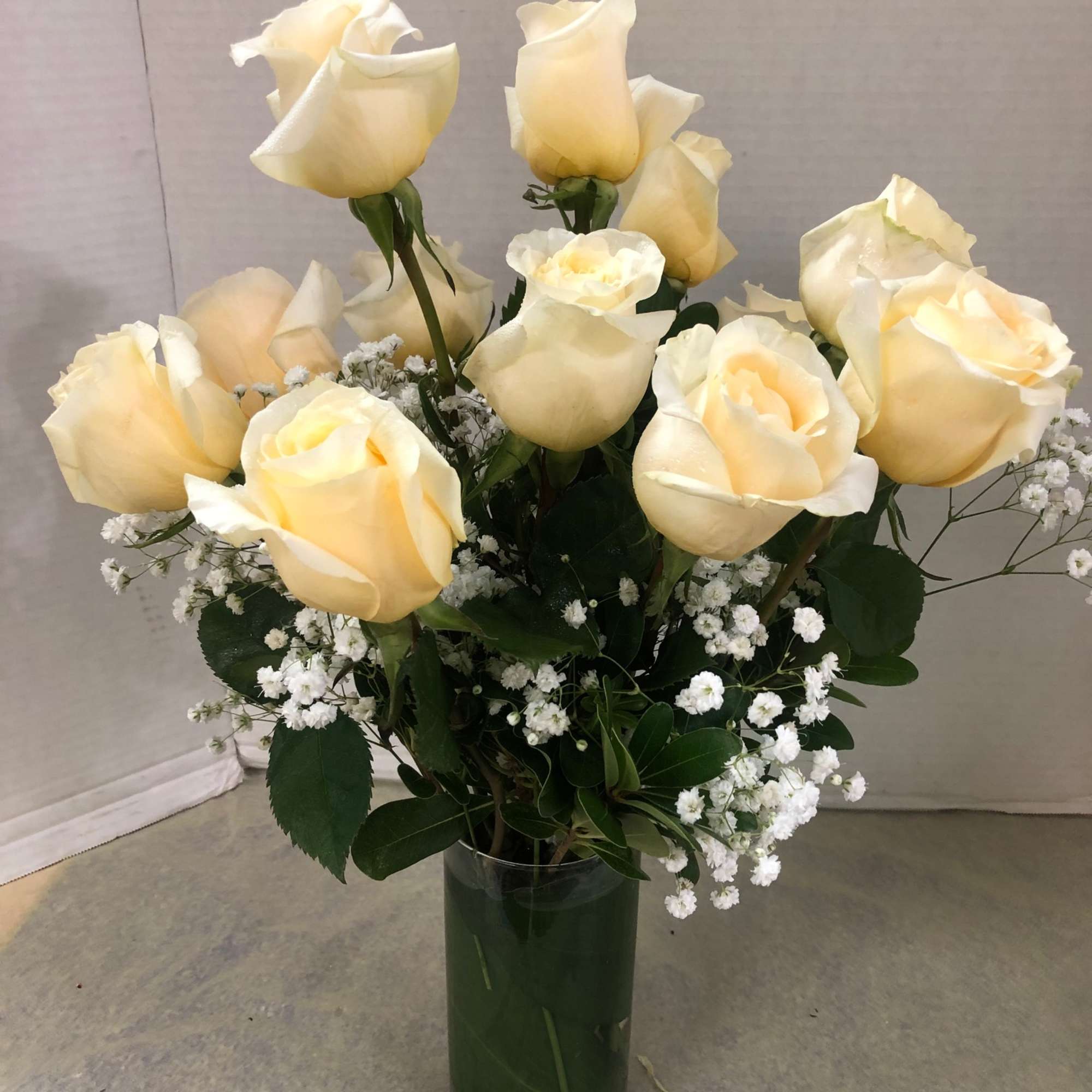 Cream roses arranged in a clear glass vase with small white filler flowers