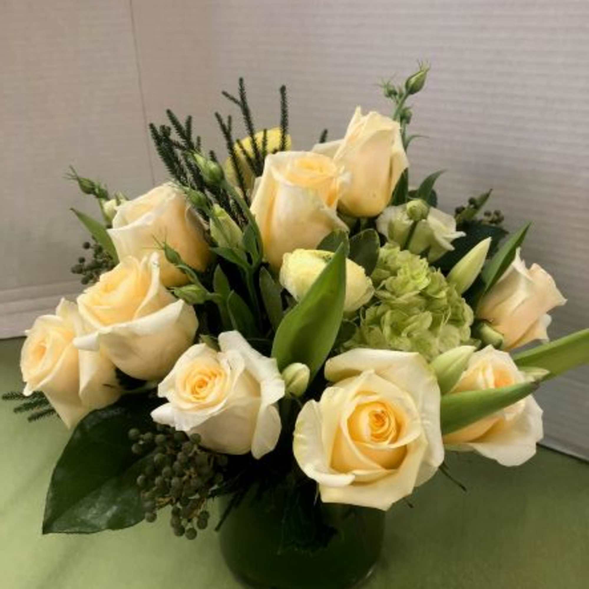 Cream roses and green hydrangea in a dark glass vase
