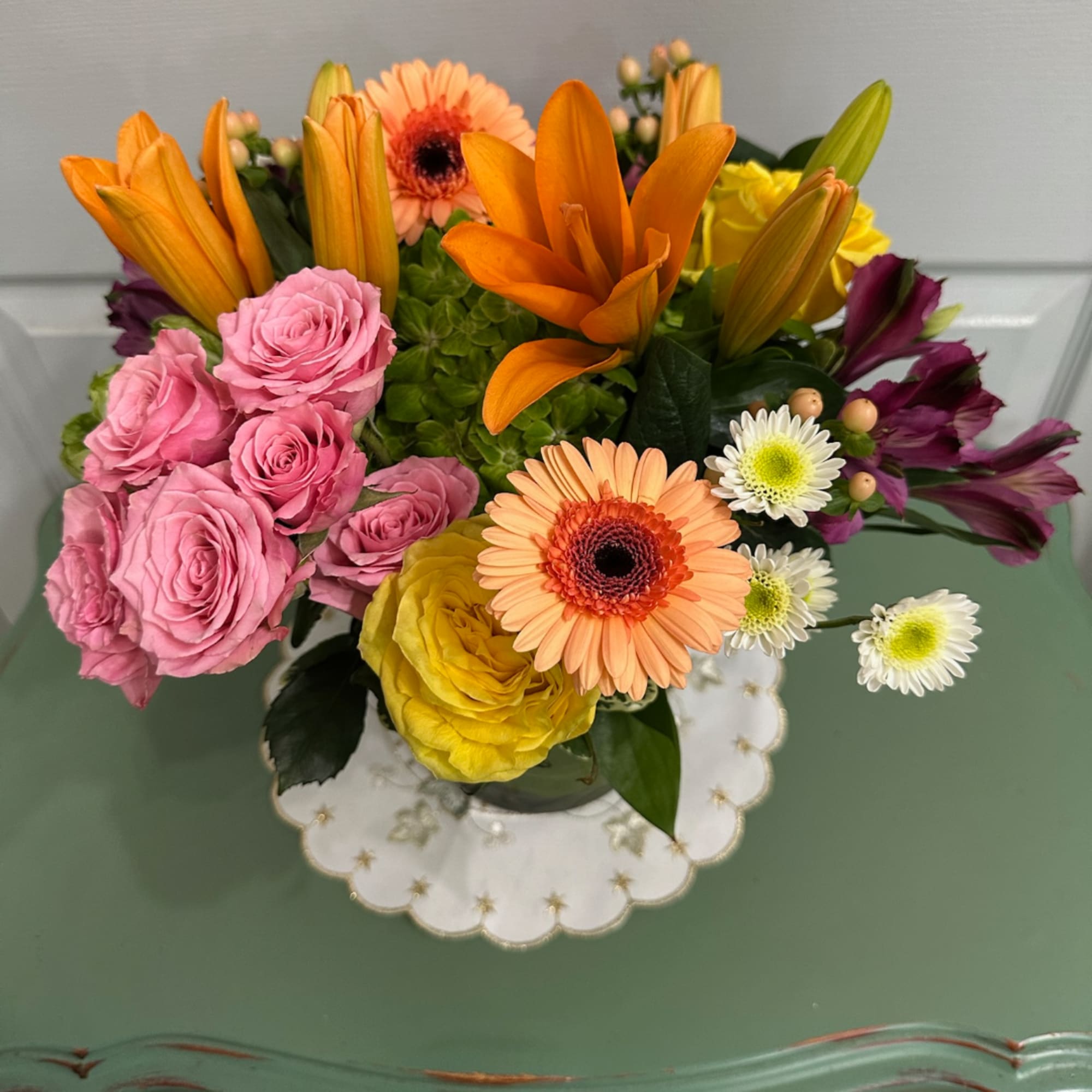 Mixed bouquet with pink roses, orange lilies, and gerbera daisies in a glass vase