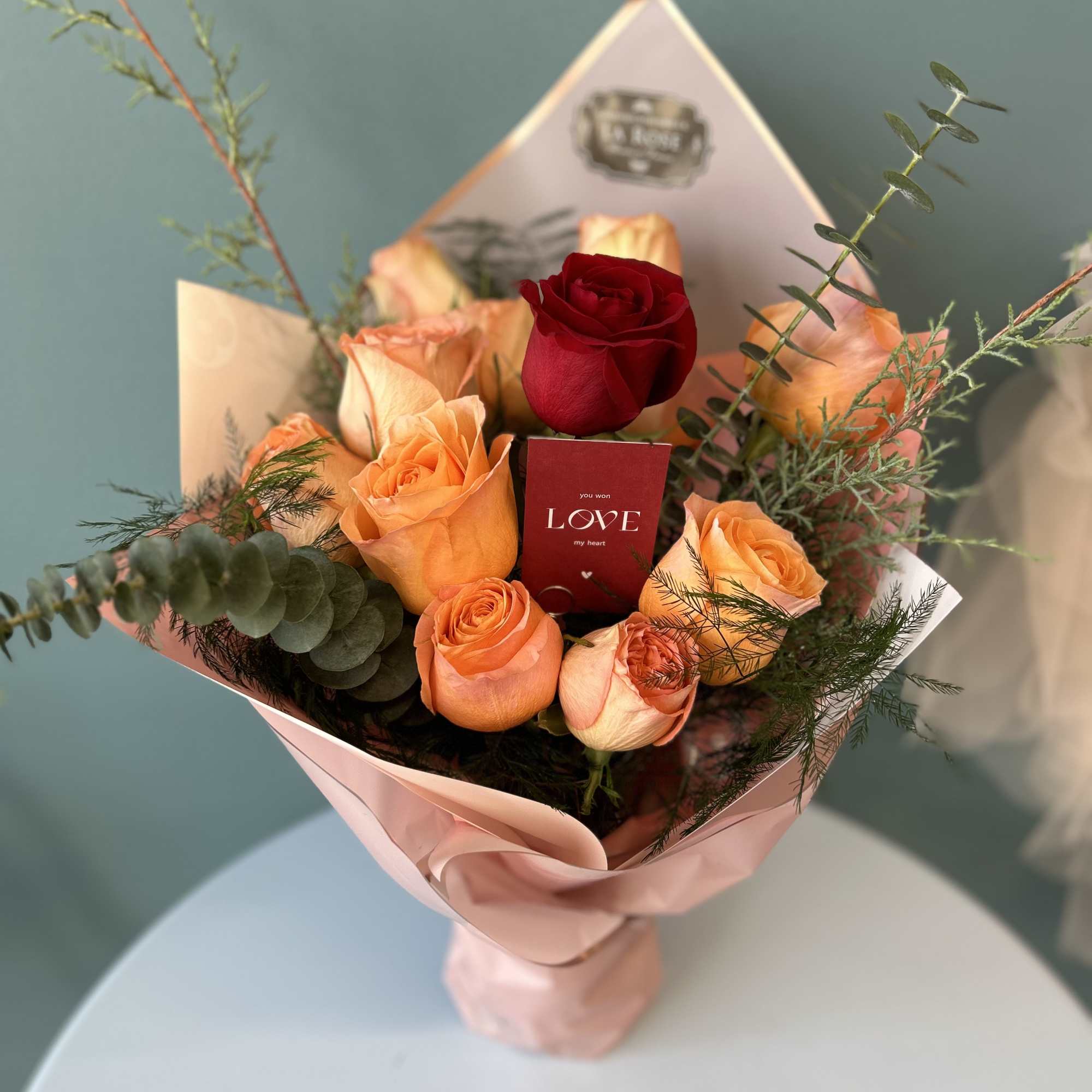 Bouquet of peach and red roses wrapped in pink paper
