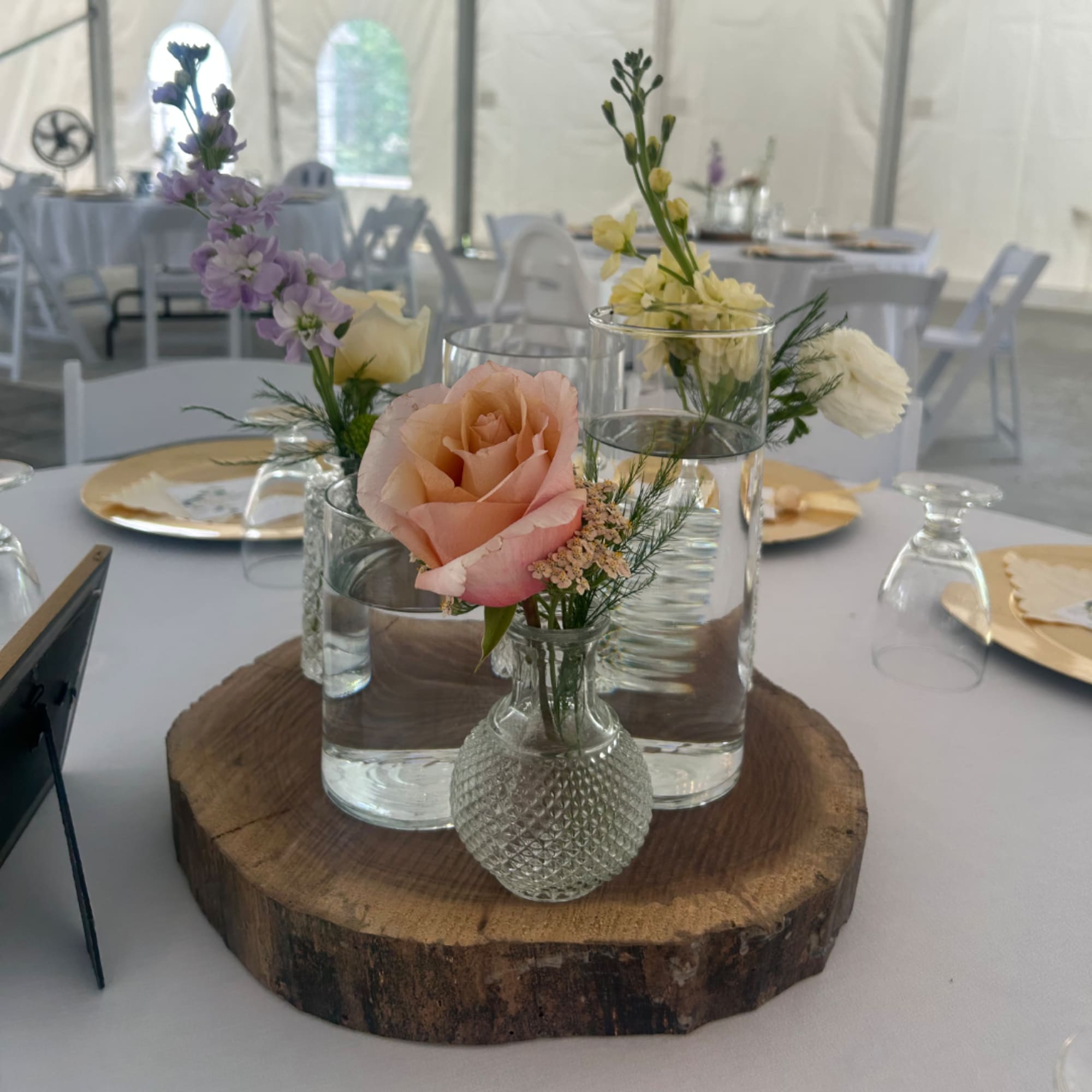 Small wedding centerpiece with roses and tall pastel blooms in glass vases