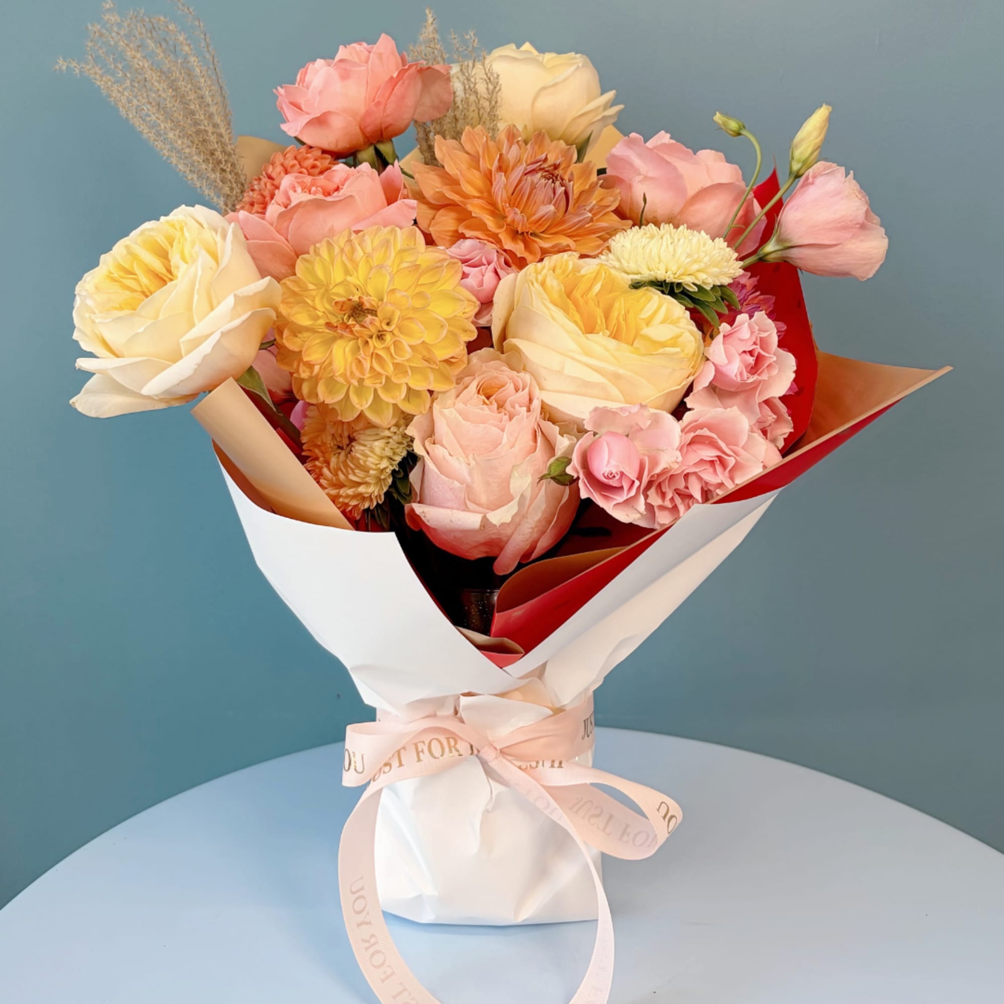 Bouquet of pink and cream roses with yellow and peach blooms in wrapping paper
