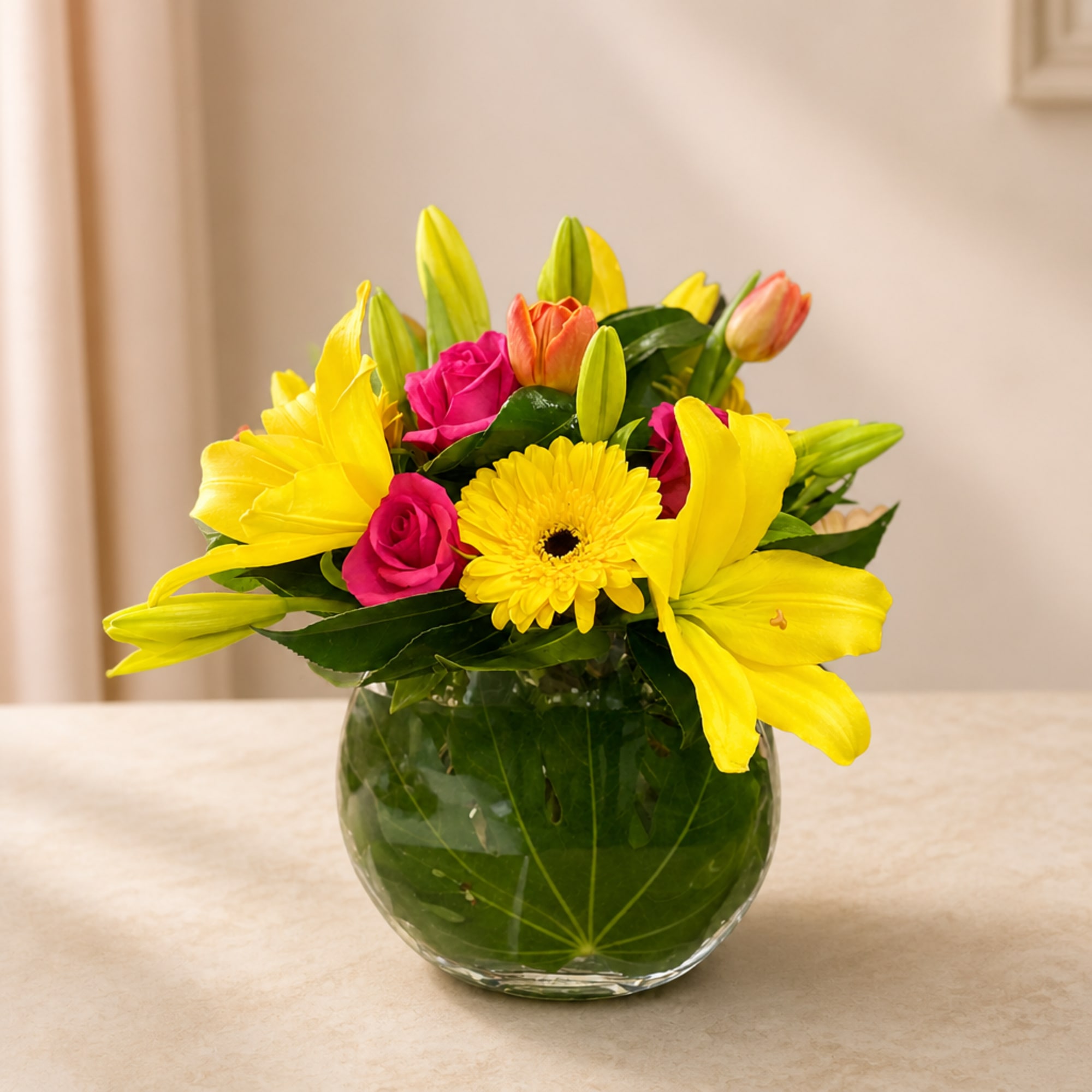Yellow lilies and pink roses in a round glass vase